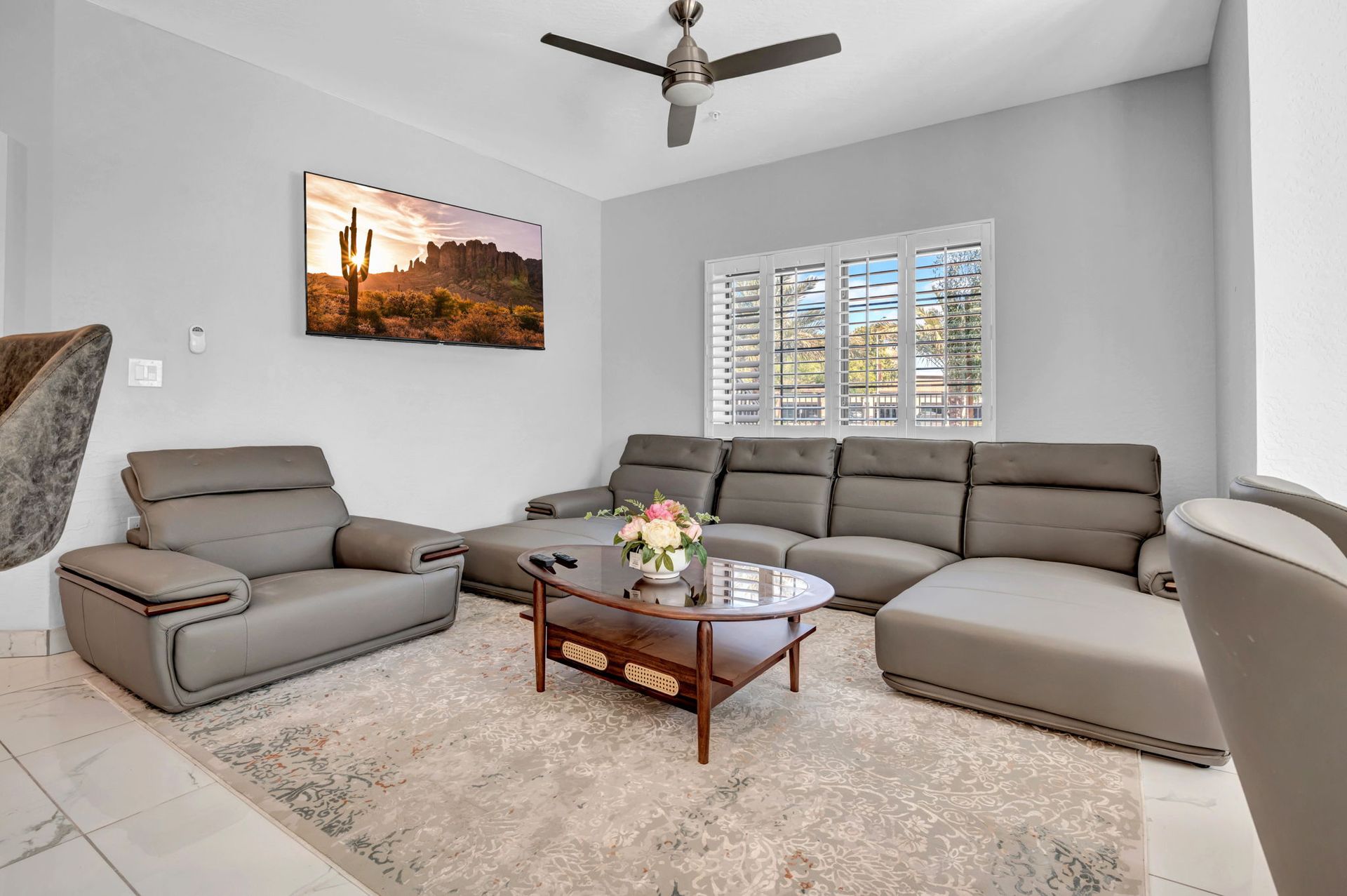 Living room with gray sectional sofa, armchair, coffee table, and desert landscape art.