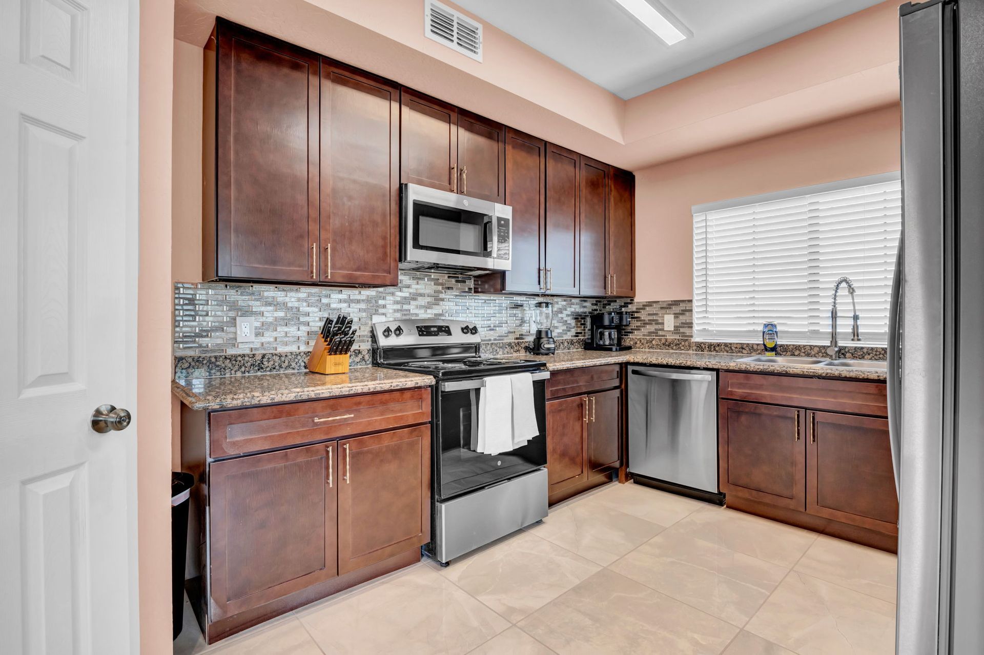 Kitchen with dark wood cabinets, stainless steel appliances, and granite countertops.