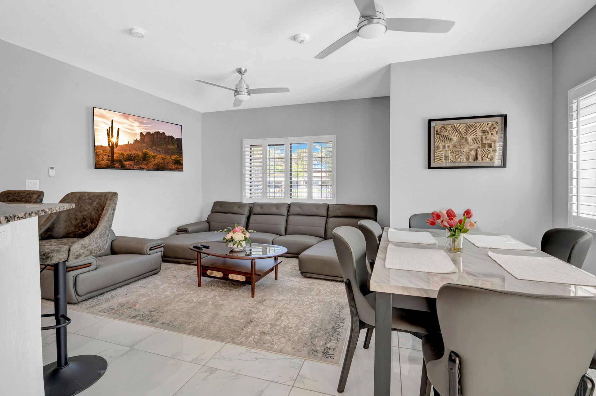 Living room with gray sectional sofa, dining table, rug, and art on wall.