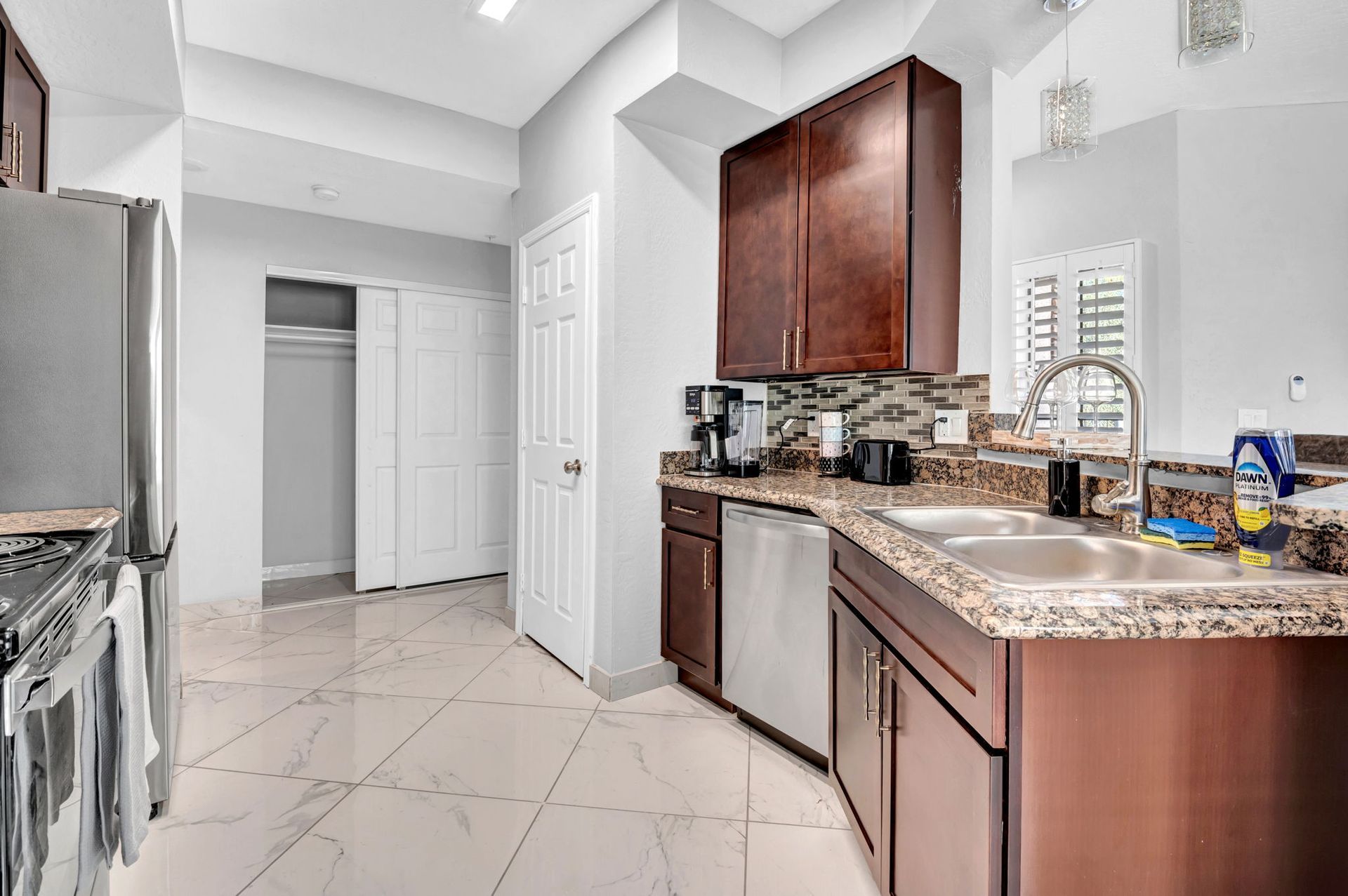 Kitchen with brown cabinets, stainless steel appliances, and tile floor.