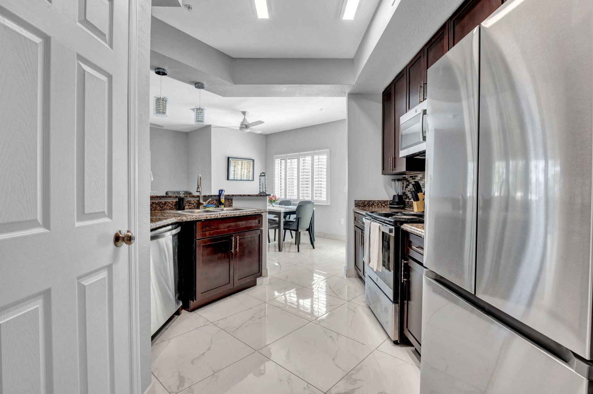 Kitchen with stainless steel appliances, dark cabinets, and dining area visible in the background.
