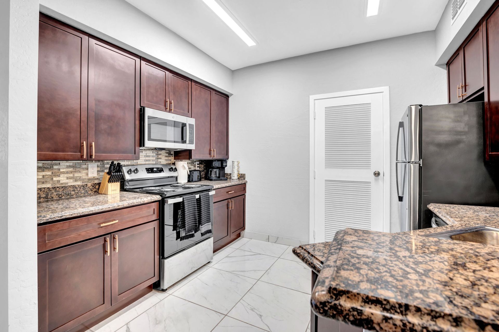 Kitchen with dark wood cabinets, stainless steel appliances, and granite countertops.