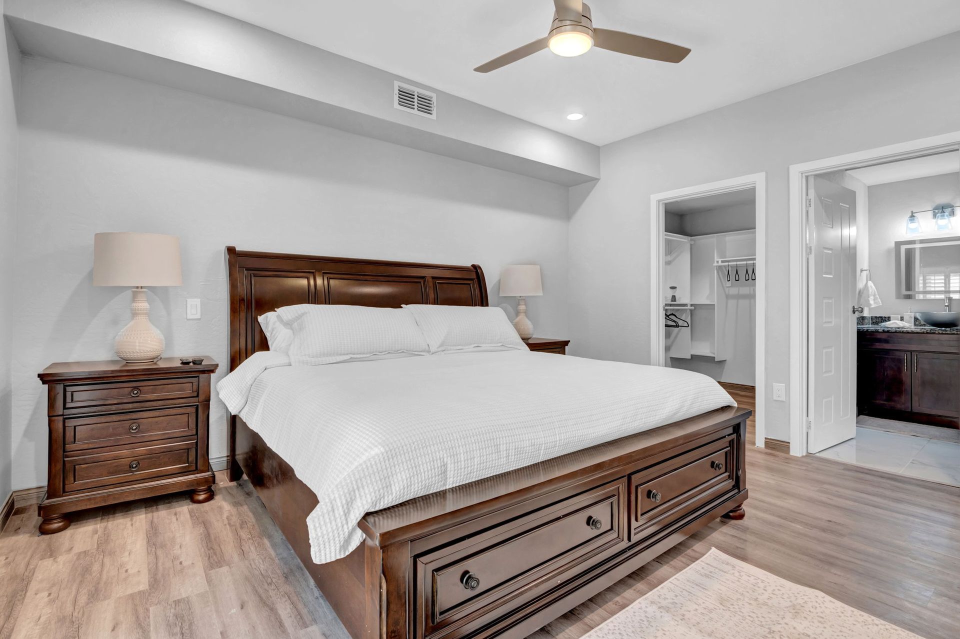 Bedroom with a large dark wood bed, two nightstands, and doorways to bathroom and closet.