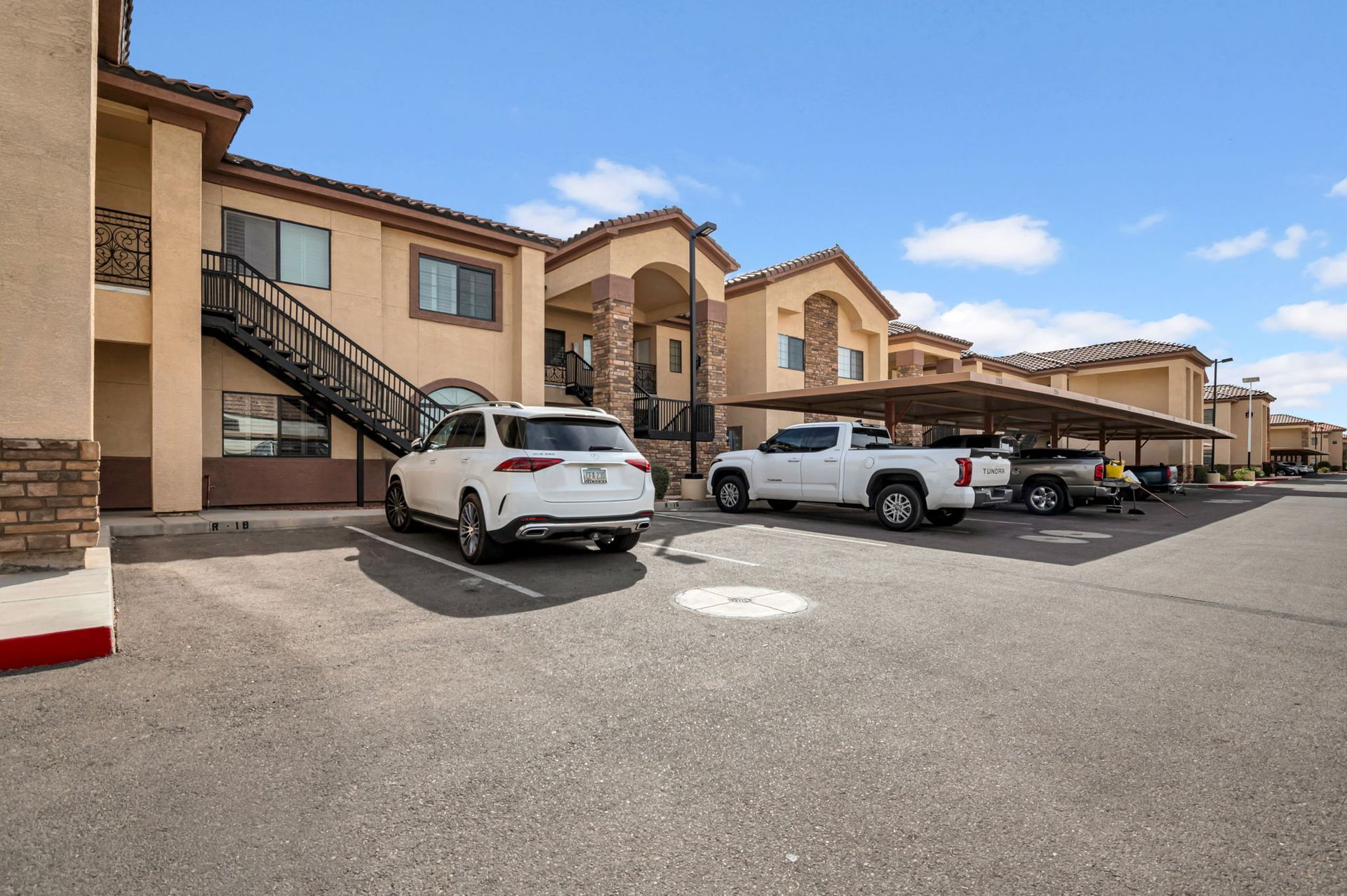 Apartment building with cars parked in front. Exterior view, sunny day.