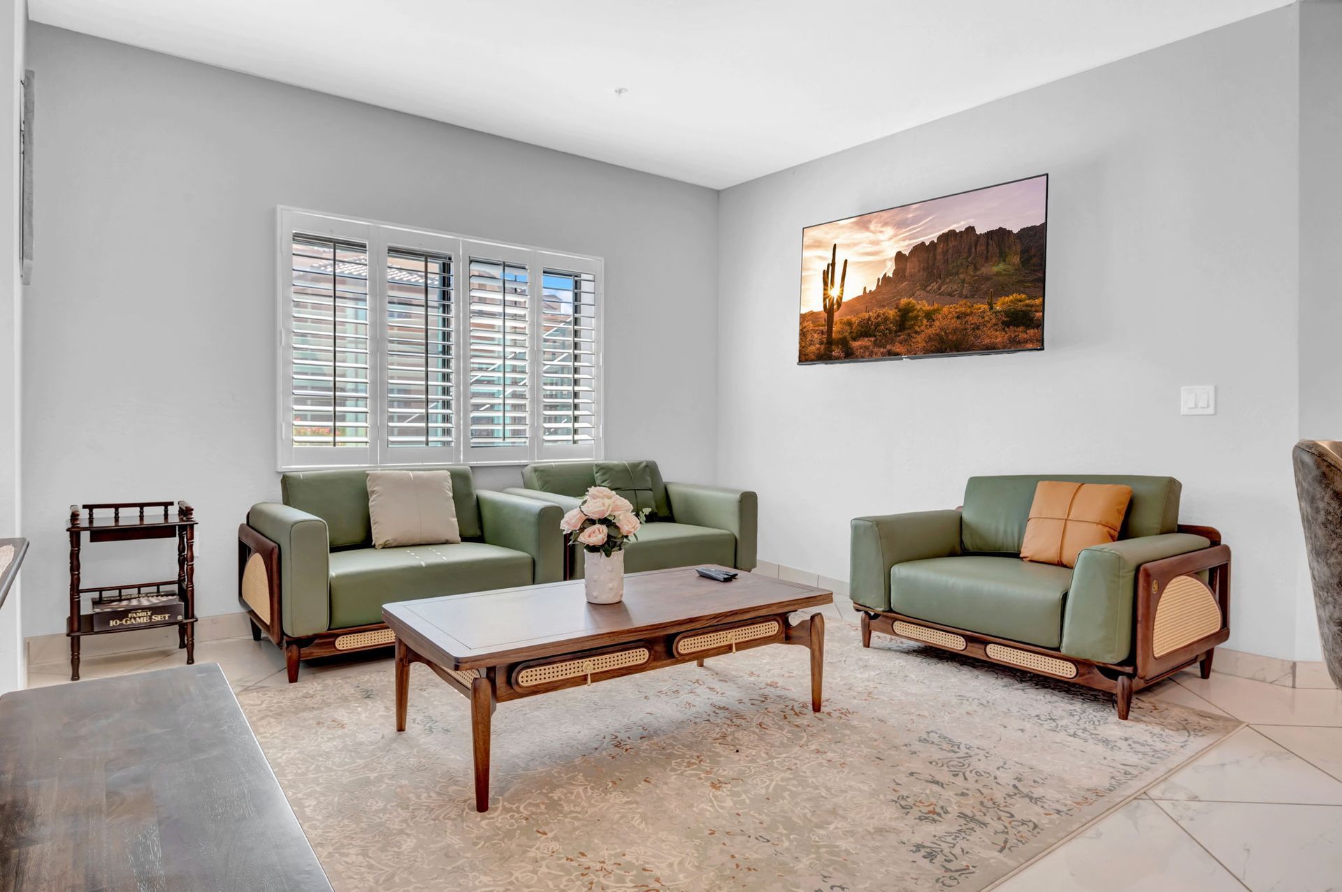 Living room with green sofas, coffee table, rug, and a landscape photo on wall.