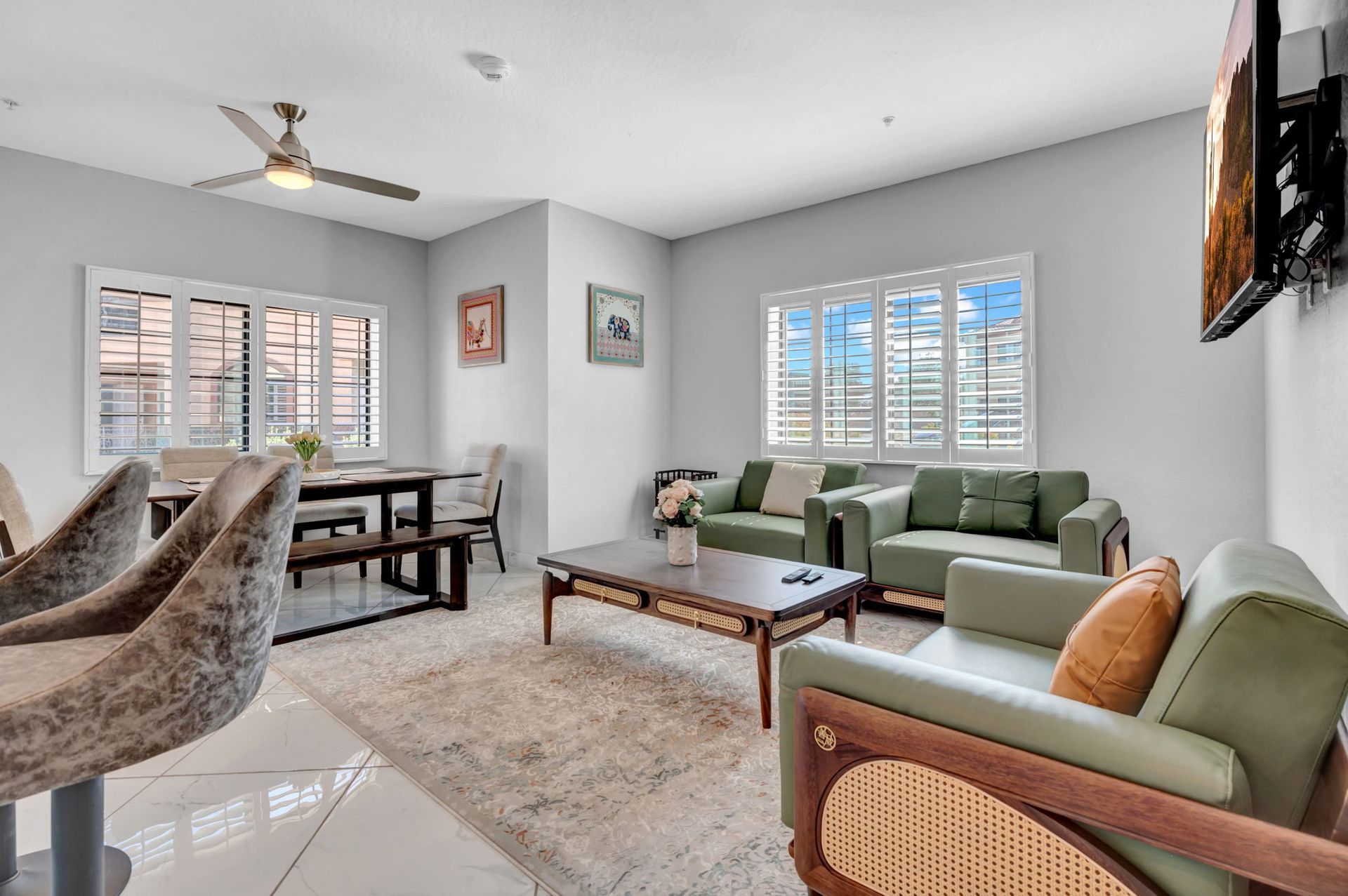 Living room with green couches, dining area, and TV on wall.