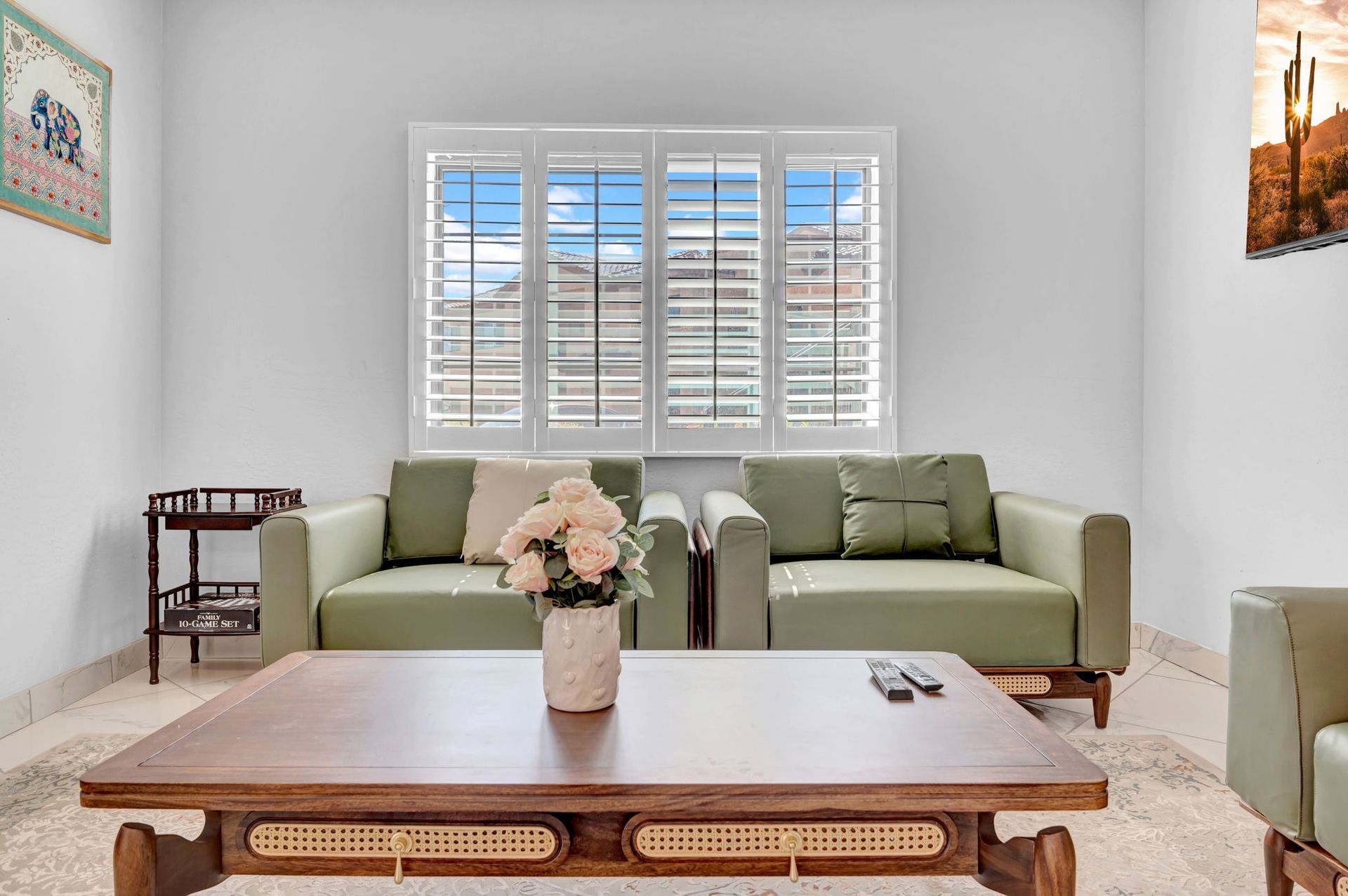 Living room with two green sofas, a wooden coffee table, and a window with a view.
