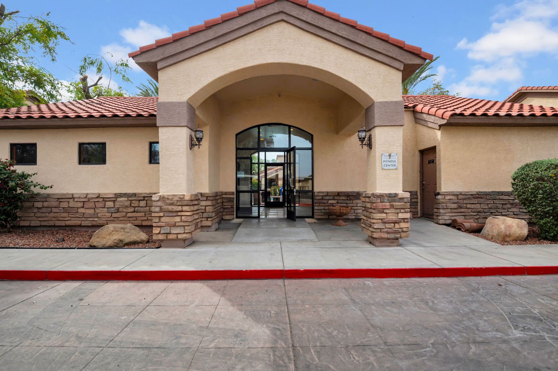 Entrance to a building with an arched doorway, brown roof, and stone accents.