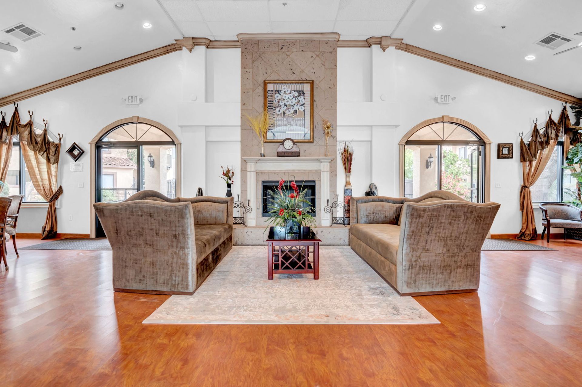 Lobby with two sofas, fireplace, and arched doorways. Wooden floor, neutral walls, and rug.
