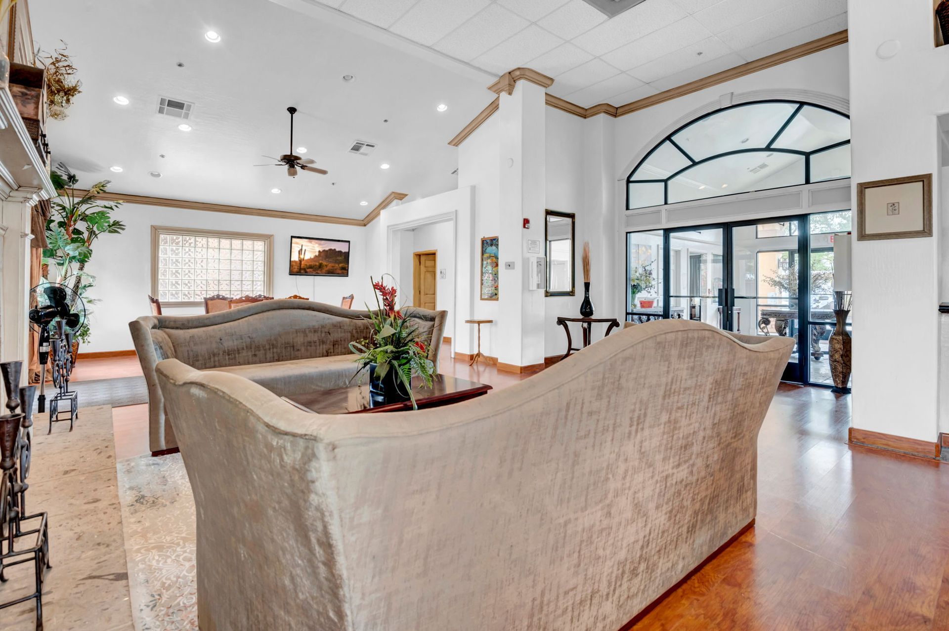 Lobby with beige sofas, wood floors, arched doorway, and decorative trim.