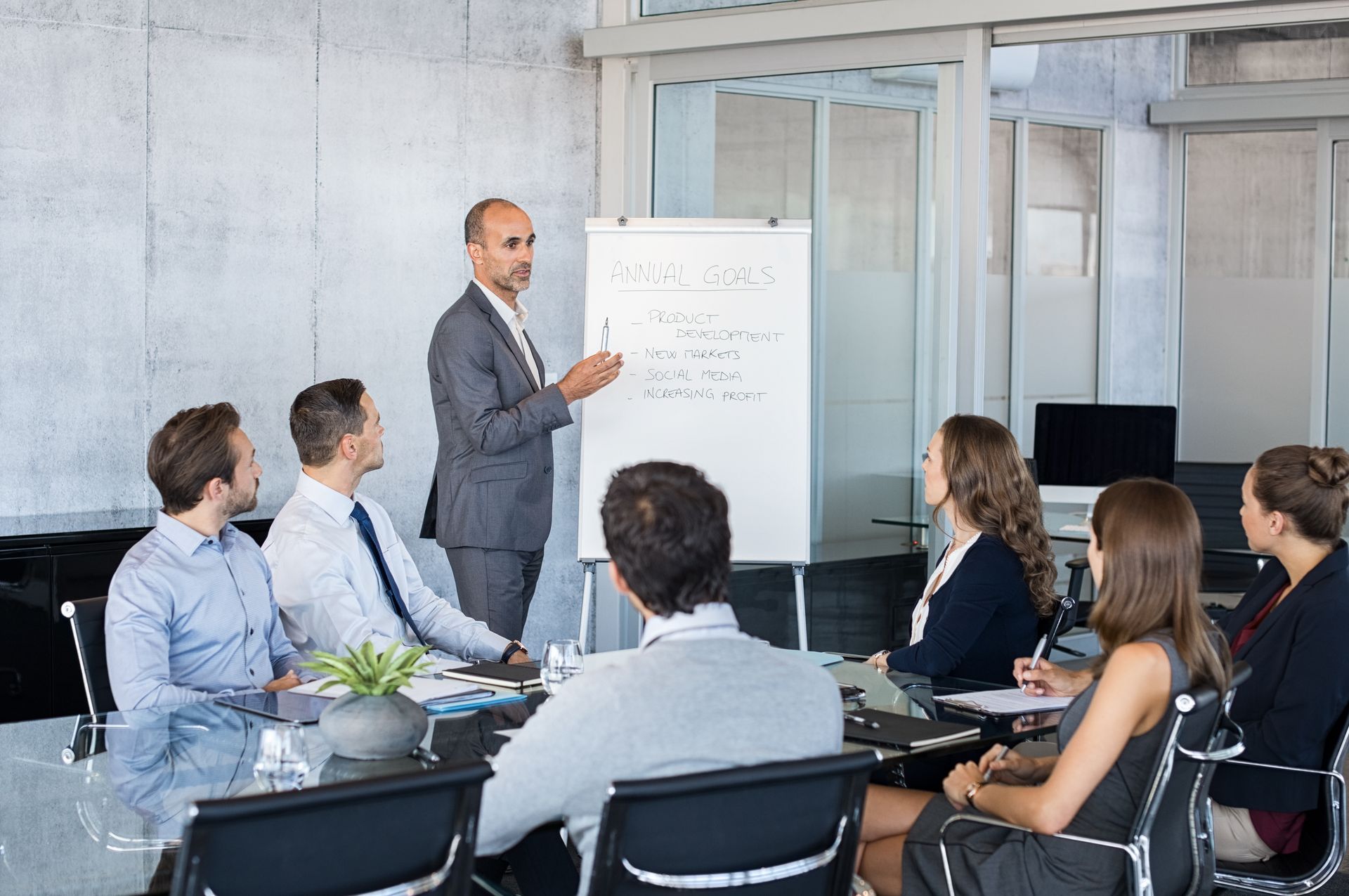 A man giving a presentation to a group of people sitting around a table.