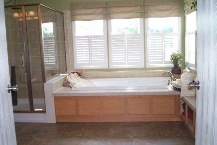 A bathroom with a jacuzzi tub and shutters on the windows