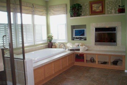 A bathroom with a jacuzzi tub and a television on the wall.