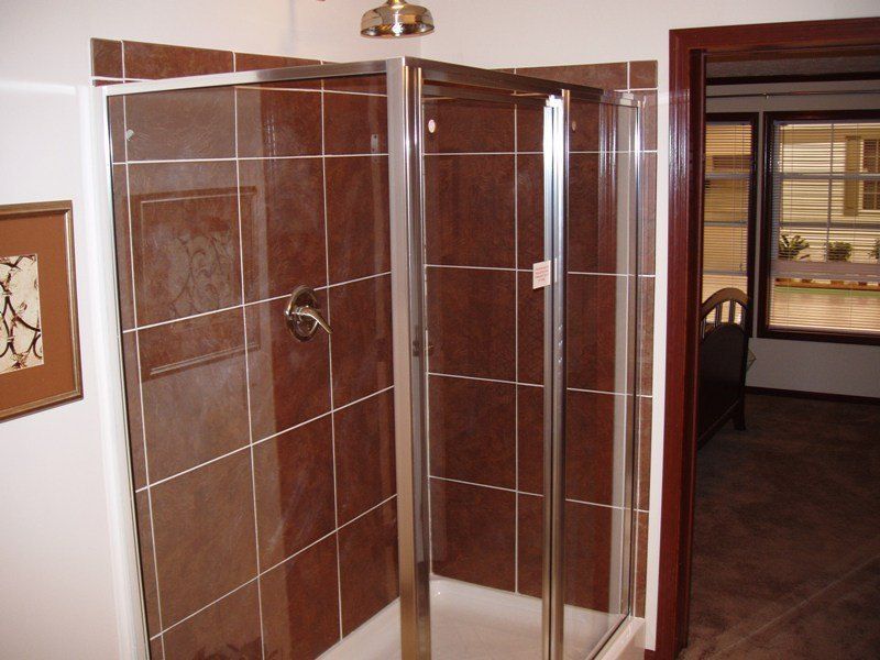 A bathroom with brown tiles and a walk in shower