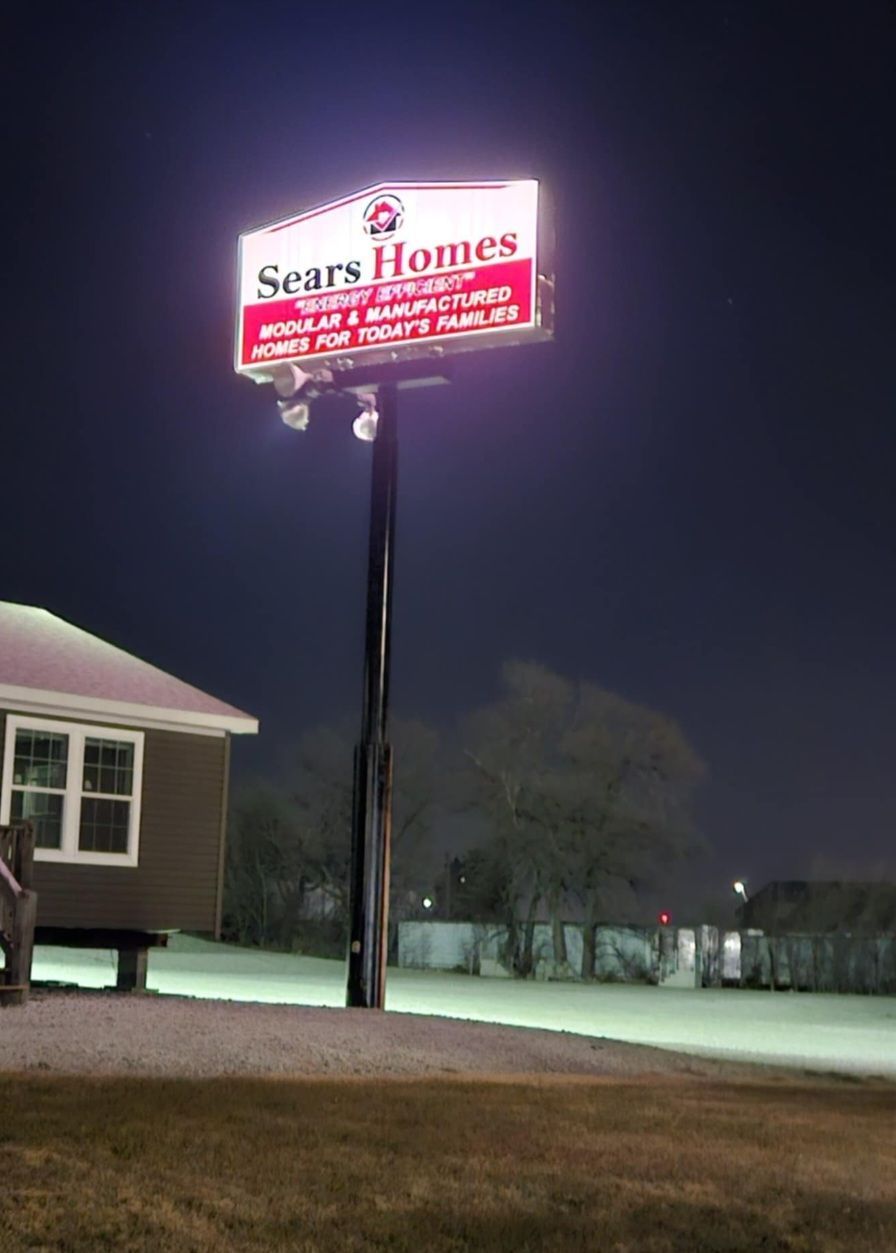 A large white house with two garages and a lush green lawn.