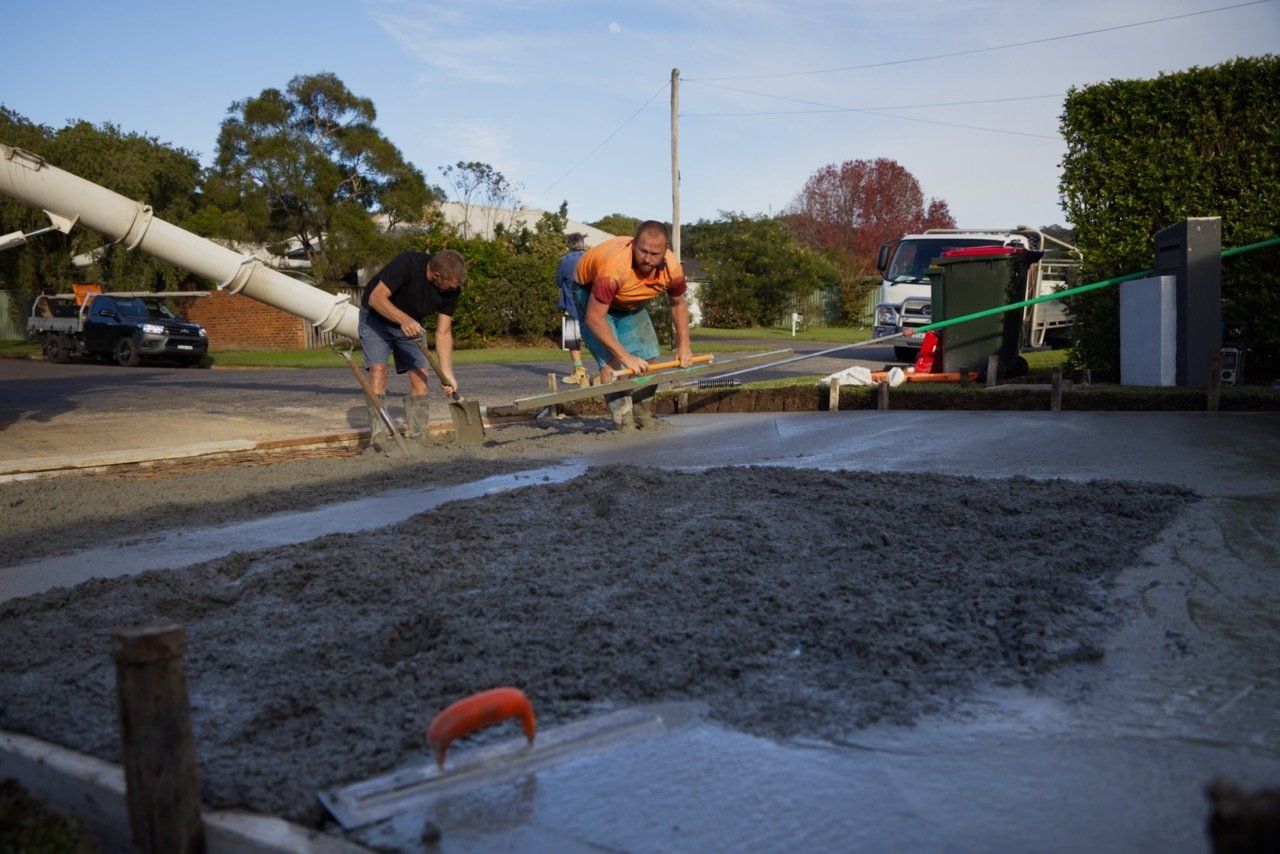 Two Men Are Working on A Concrete Driveway with A Truck in The Background — Easy Mix Concrete in Berkeley Vale, NSW