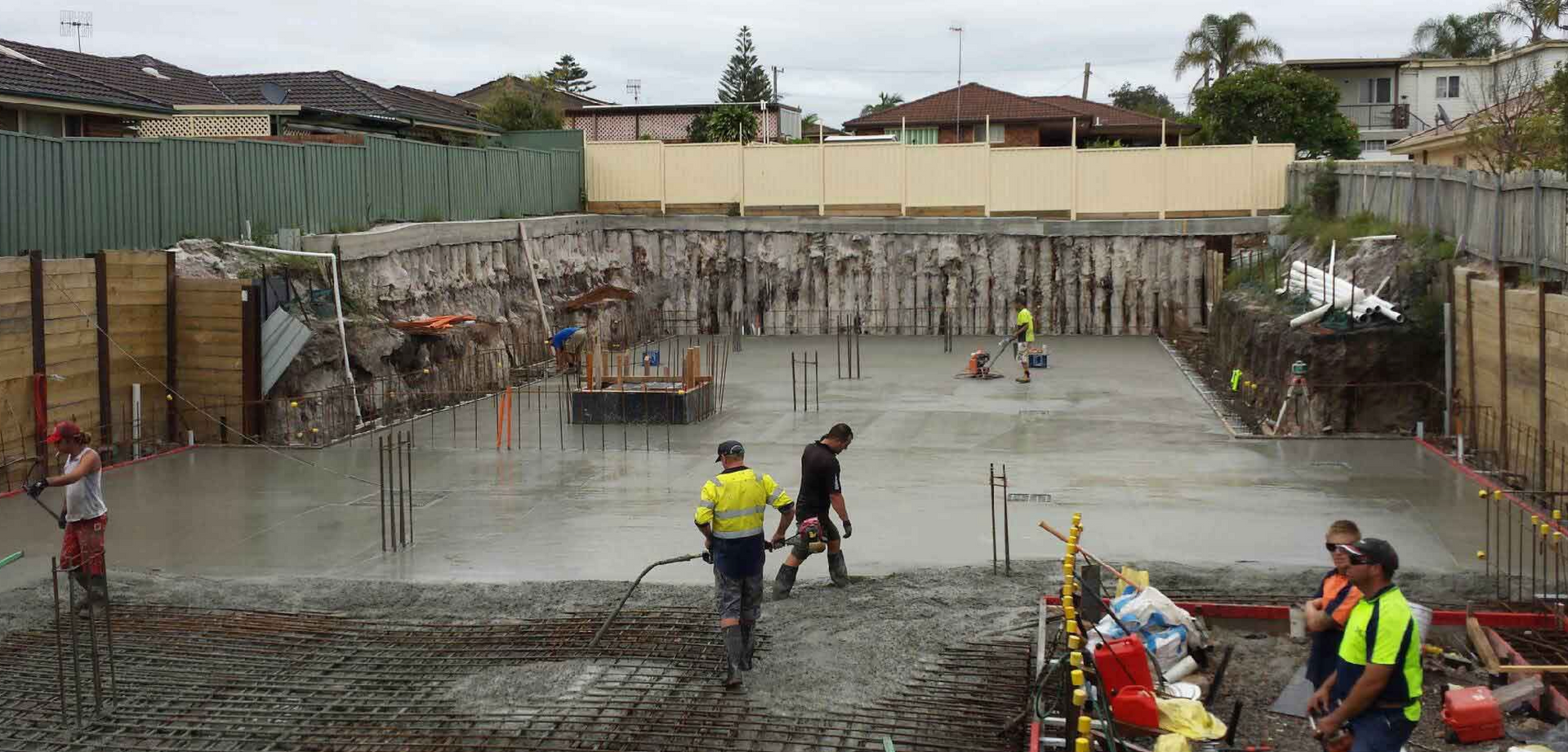 Several concrete layers working on a large site filled with fresh, wet concrete. 