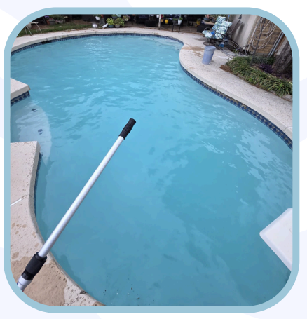 Pool being cleaned with a telescopic pole; turquoise water, stone coping, lush greenery.