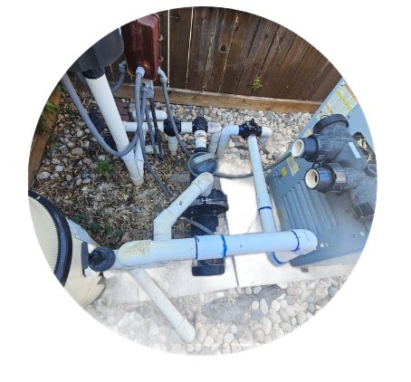 Pool equipment including pump, filter, heater, and pipes, outdoors near a fence.