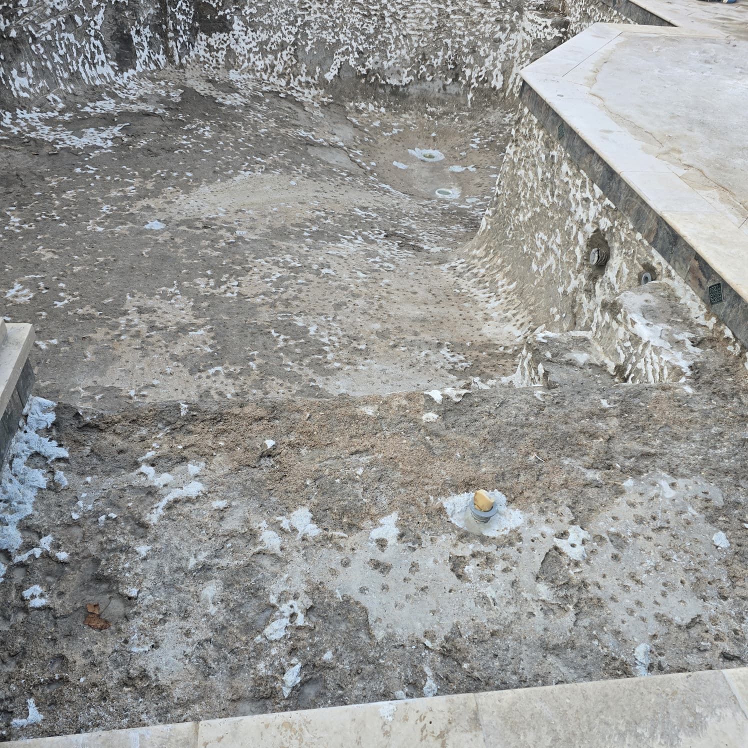 Empty concrete swimming pool with chipped edges and steps.
