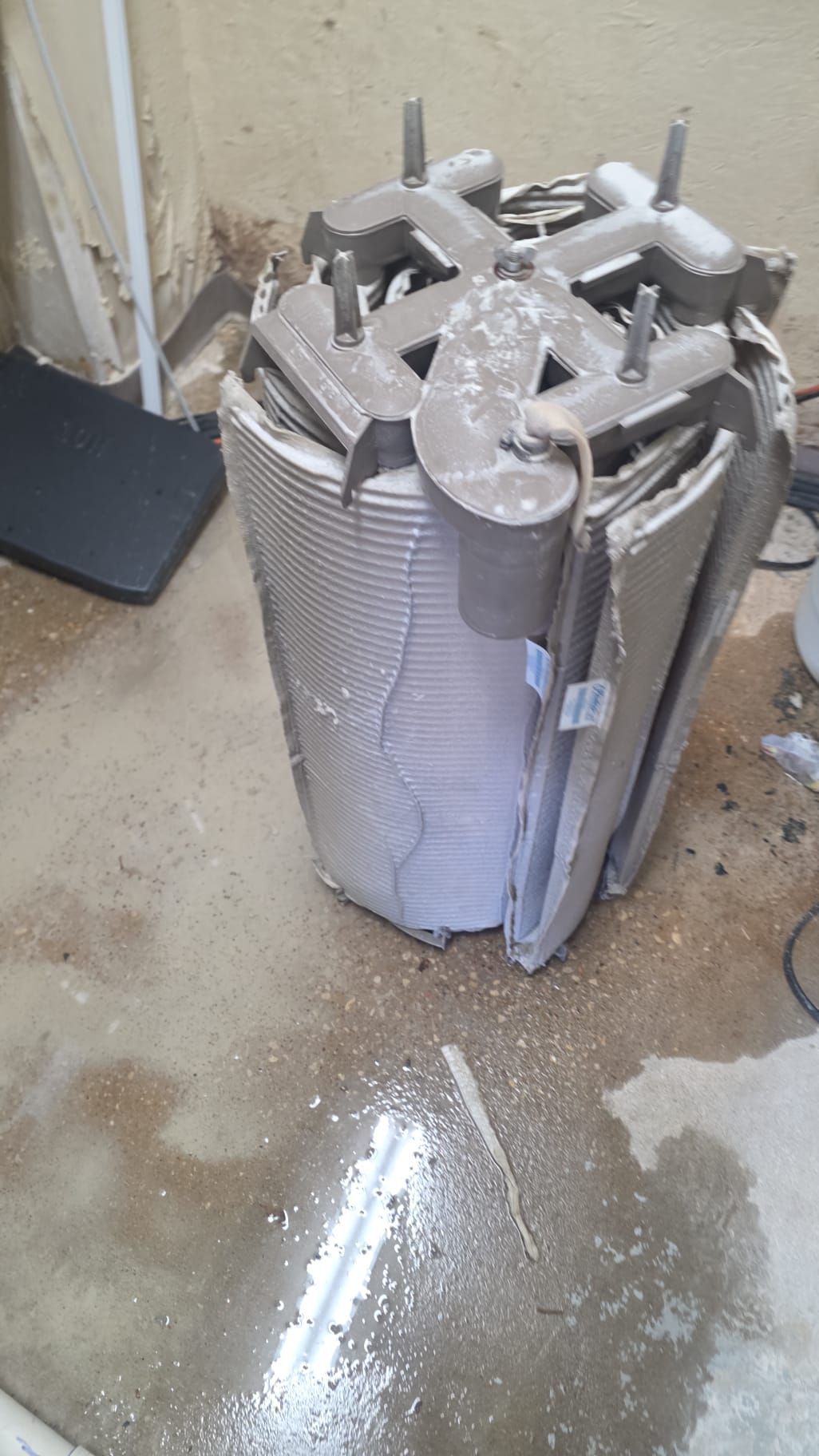 A damaged electrical transformer core, lying on a concrete floor with debris.