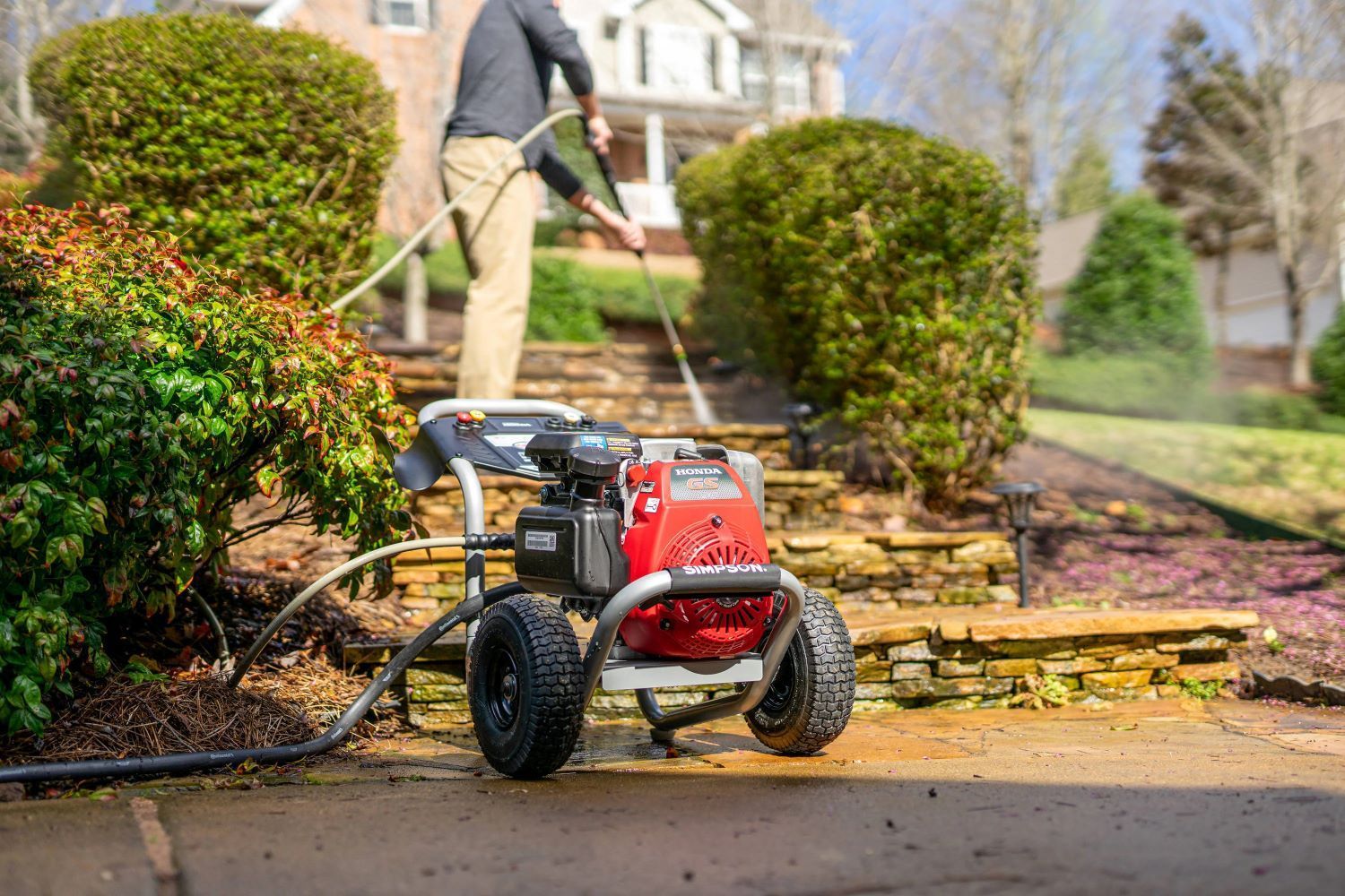Pressure washer cleaning stone steps in front yard. A person sprays the steps.