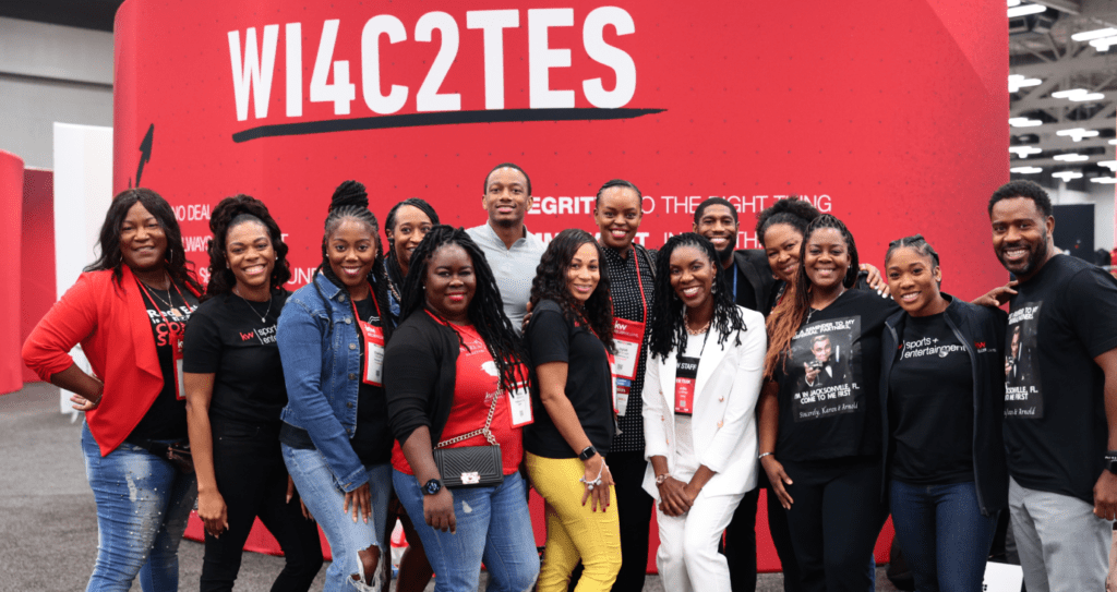 A group of people are posing for a picture in front of a red wall.