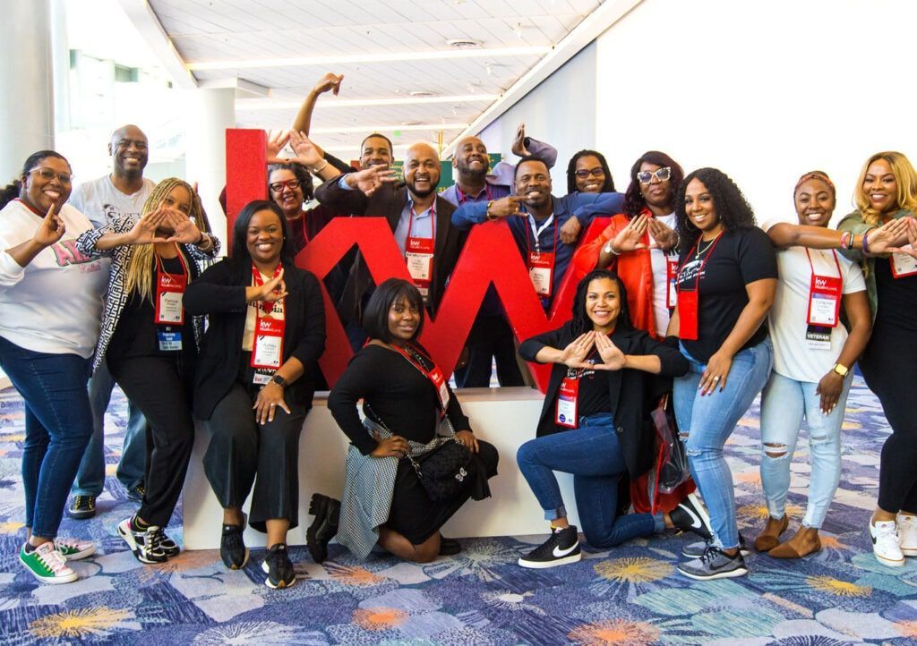 A group of people are posing for a picture in front of a large red sign.