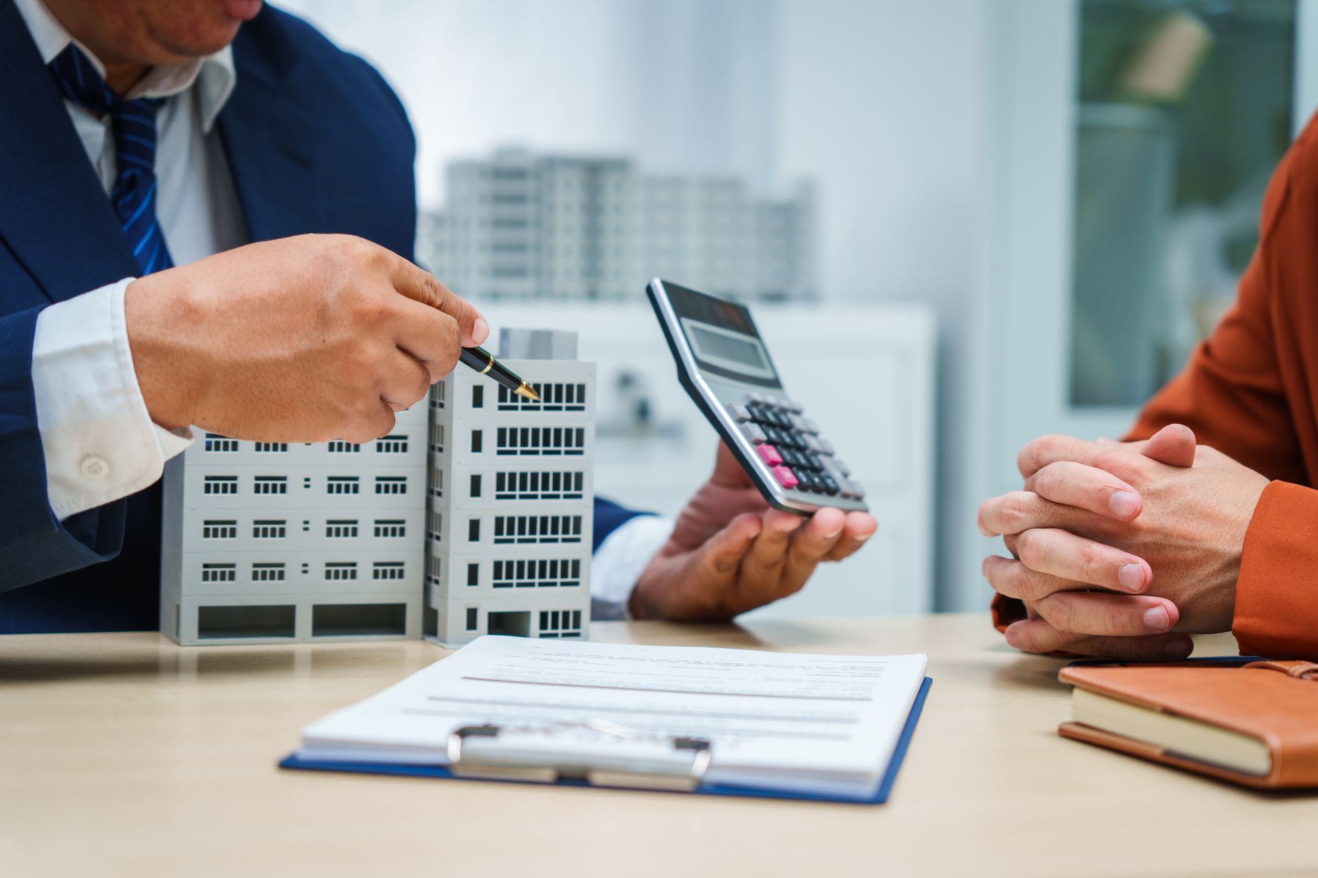 A man is holding a calculator and pointing at a model building.