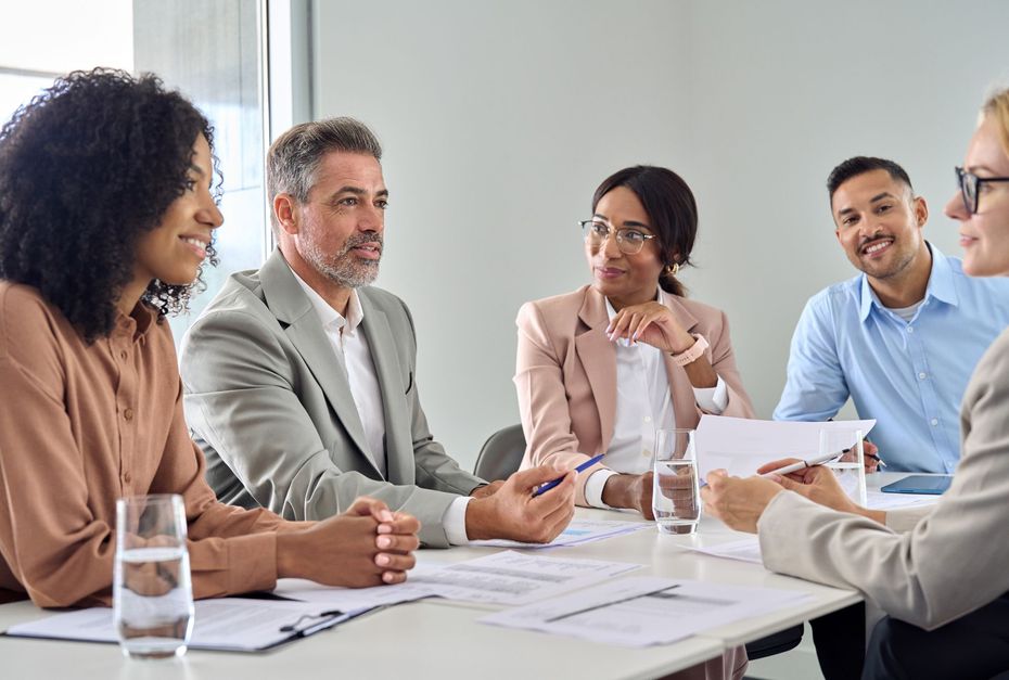 A group of people are sitting around a table having a meeting.