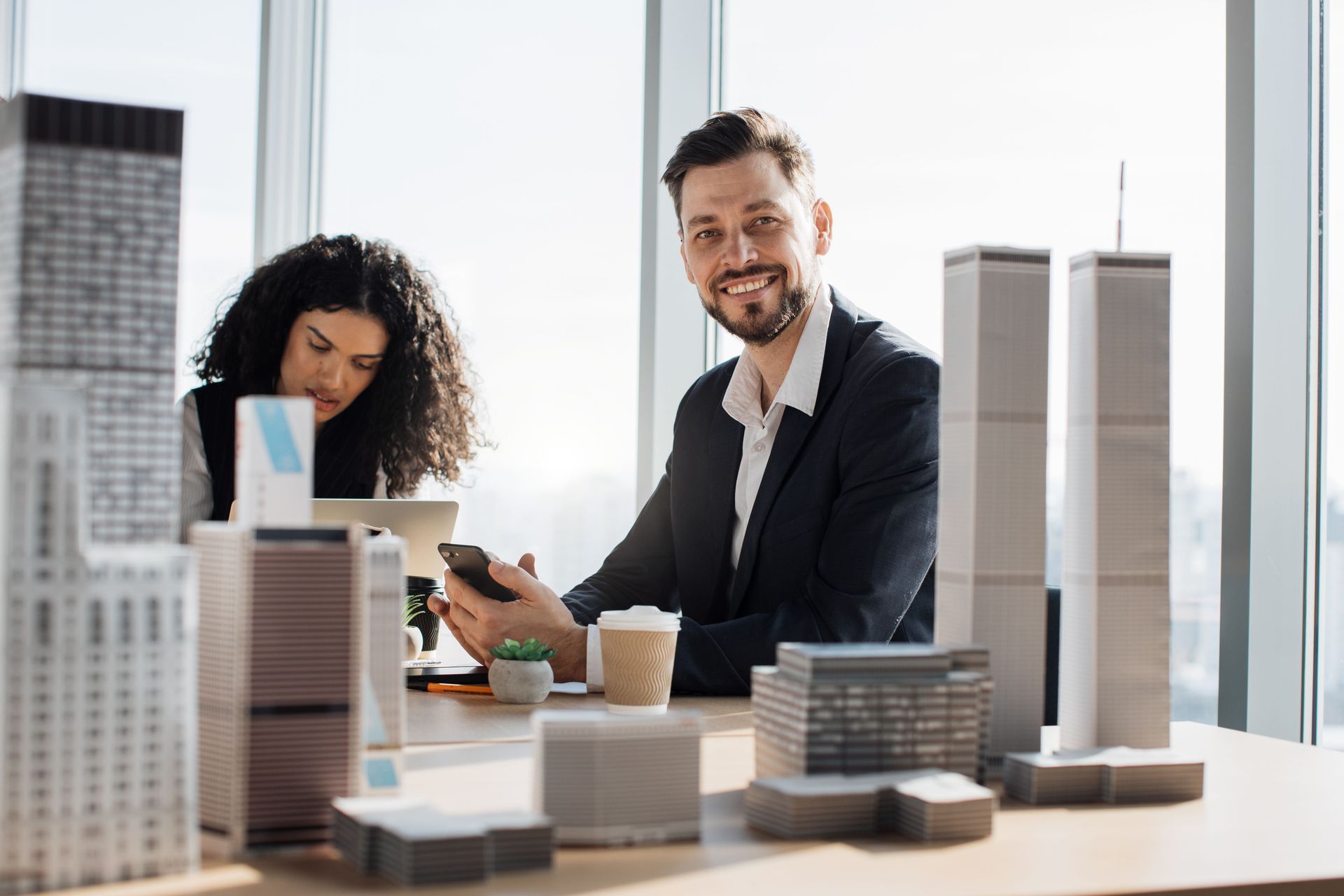 A man and a woman are sitting at a table with model buildings.