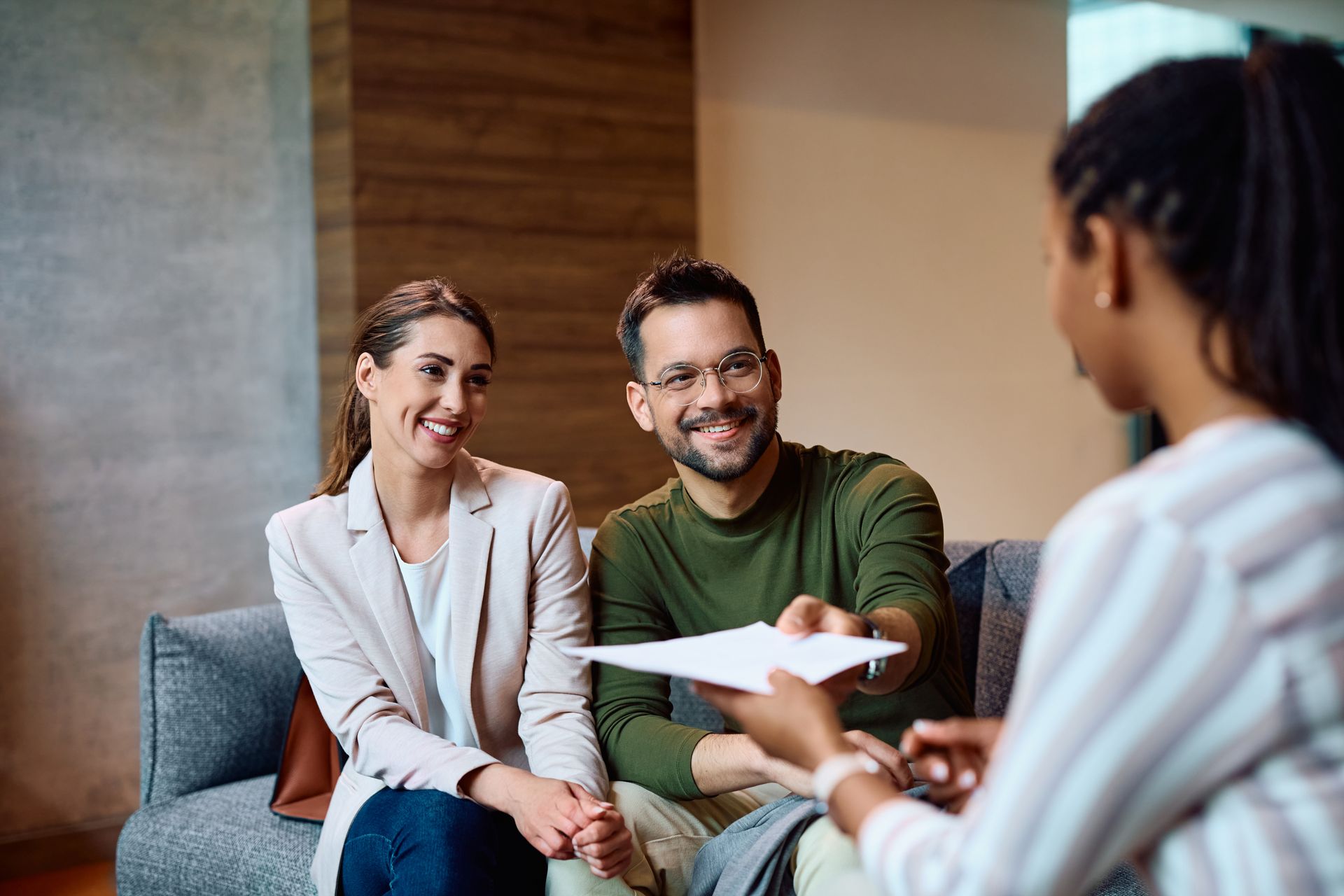A man and a woman are sitting on a couch talking to a woman.