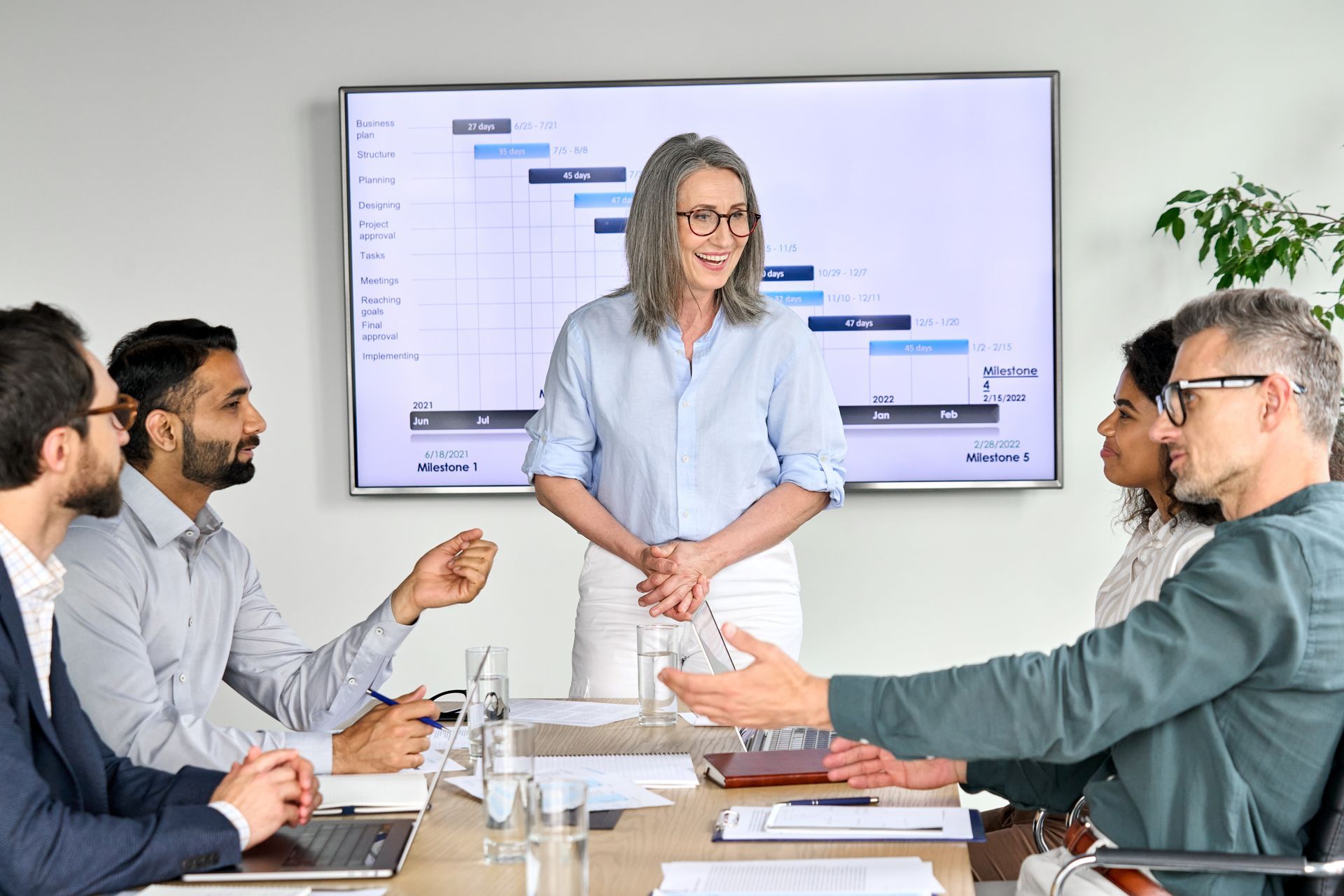 A woman is giving a presentation to a group of people at a conference table.