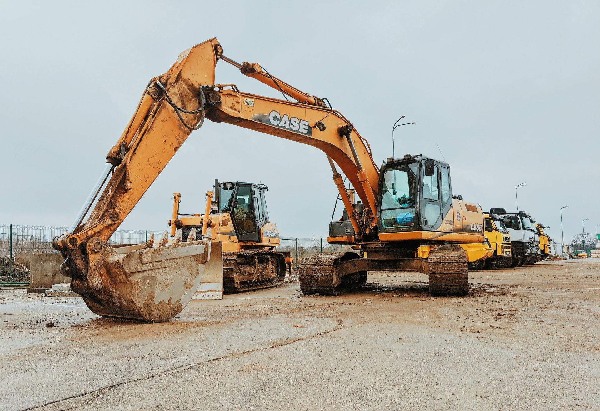 Orange excavator and bulldozer on a construction site. Cloudy sky in the background.