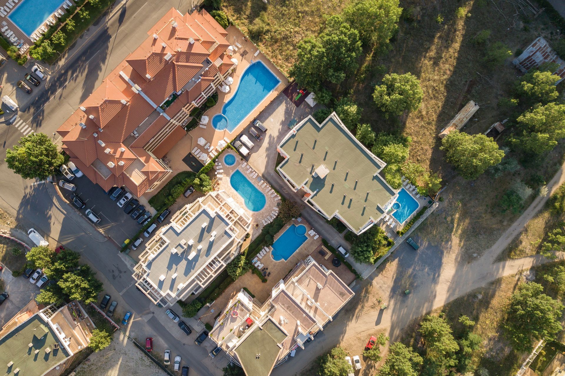Aerial view of residential buildings with pools and surrounding greenery.