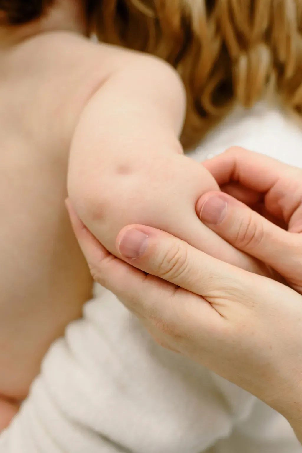 Une personne tient le bras d'un bébé dans ses mains.
