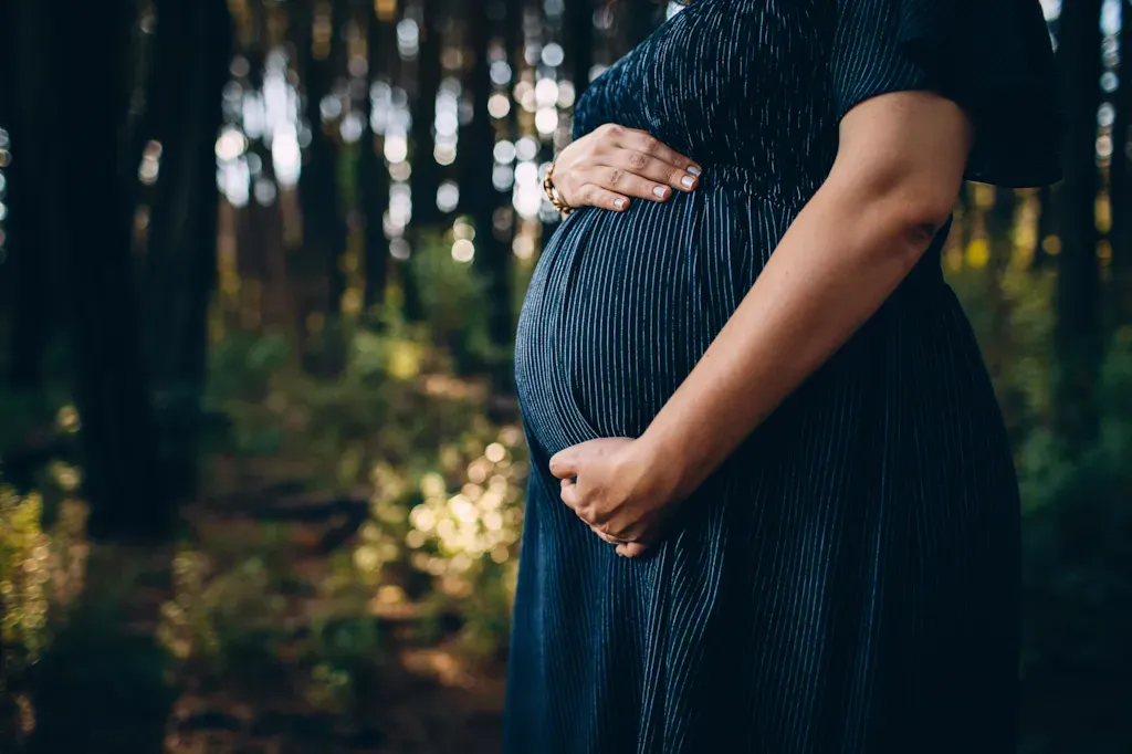 Une femme enceinte tient son ventre dans les bois.