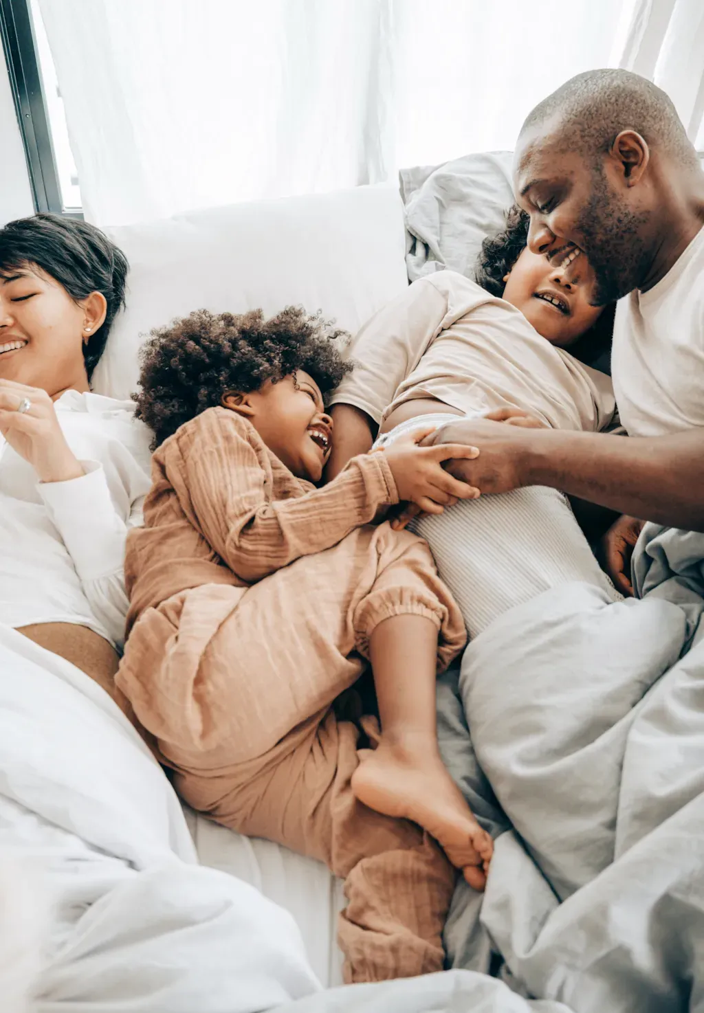 Une famille est allongée dans le lit ensemble et joue les uns avec les autres.