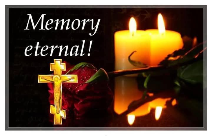 A remembrance graphic featuring a gold crucifix, red rose, two lit candles, and the words 