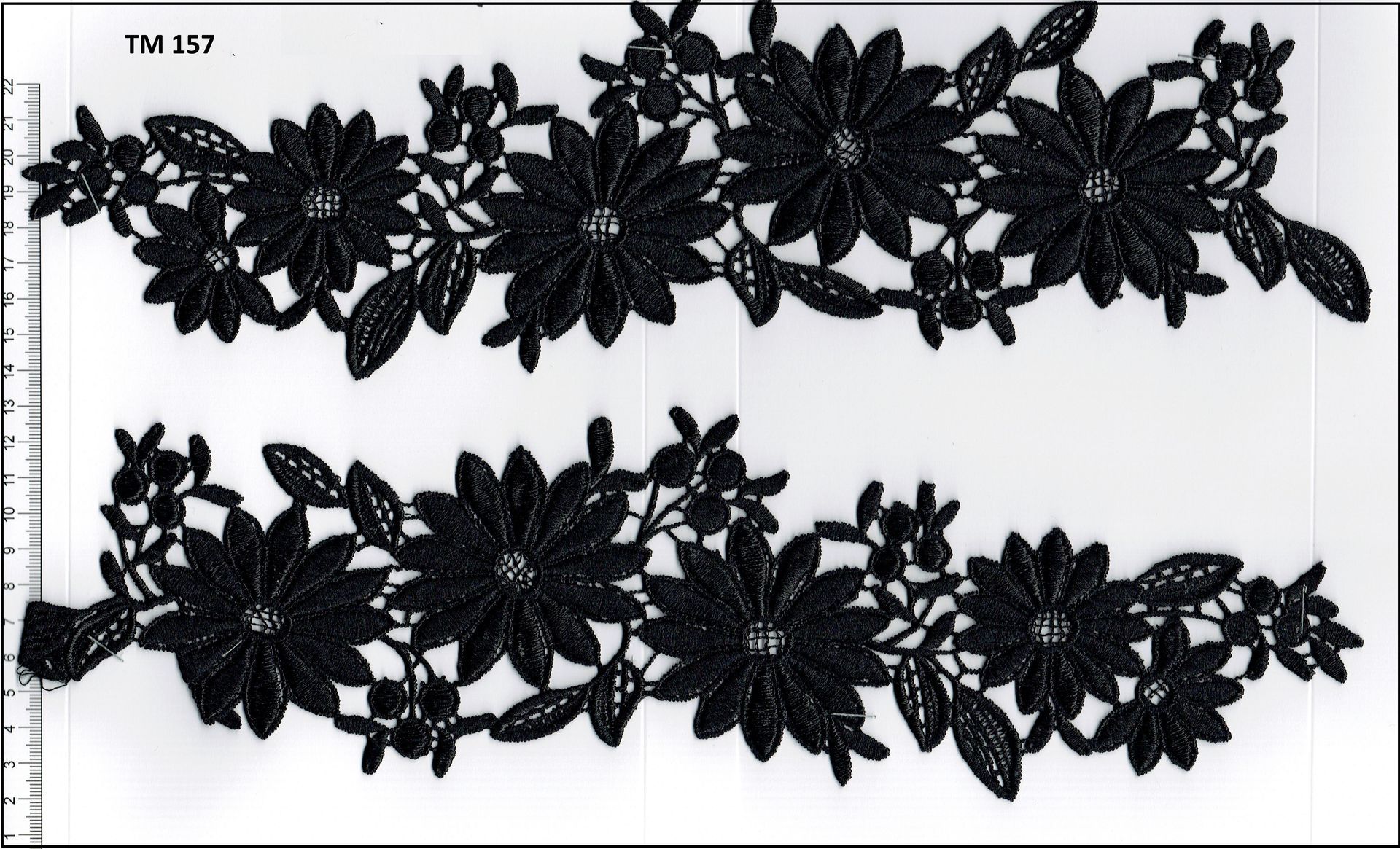 A pair of black lace flowers with a ruler in the background