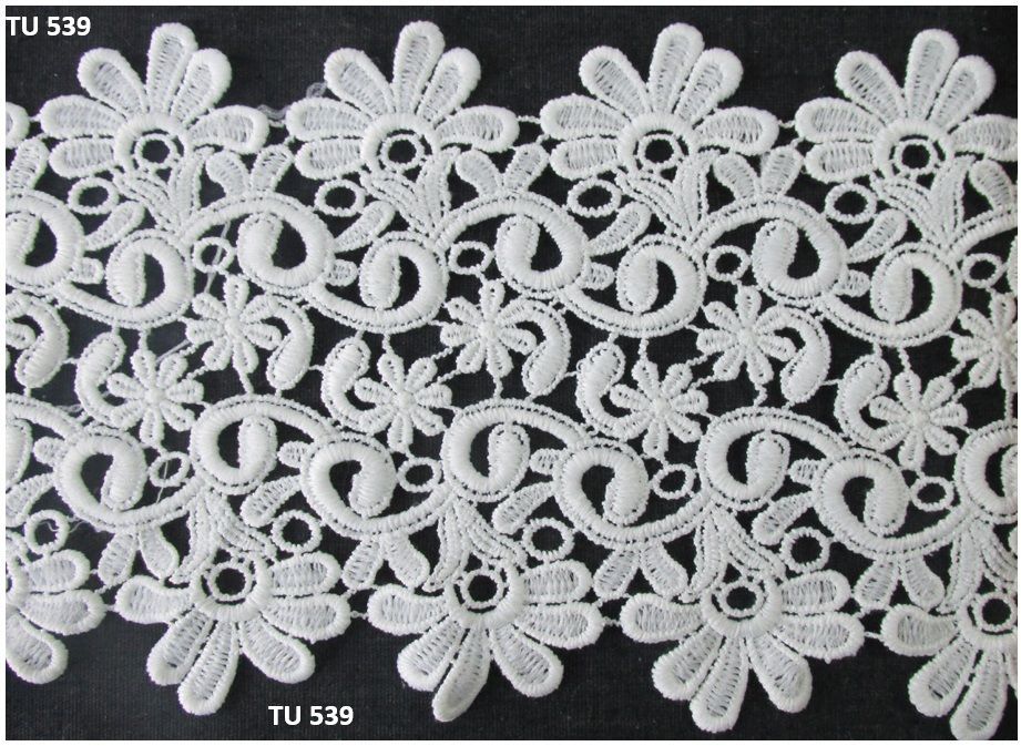 A close up of a white lace border with flowers on a black background