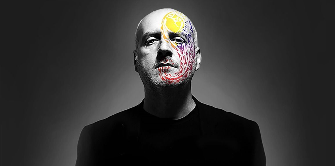 Il volto di un uomo calvo è dipinto per metà con schizzi colorati, l'altra metà è semplice.