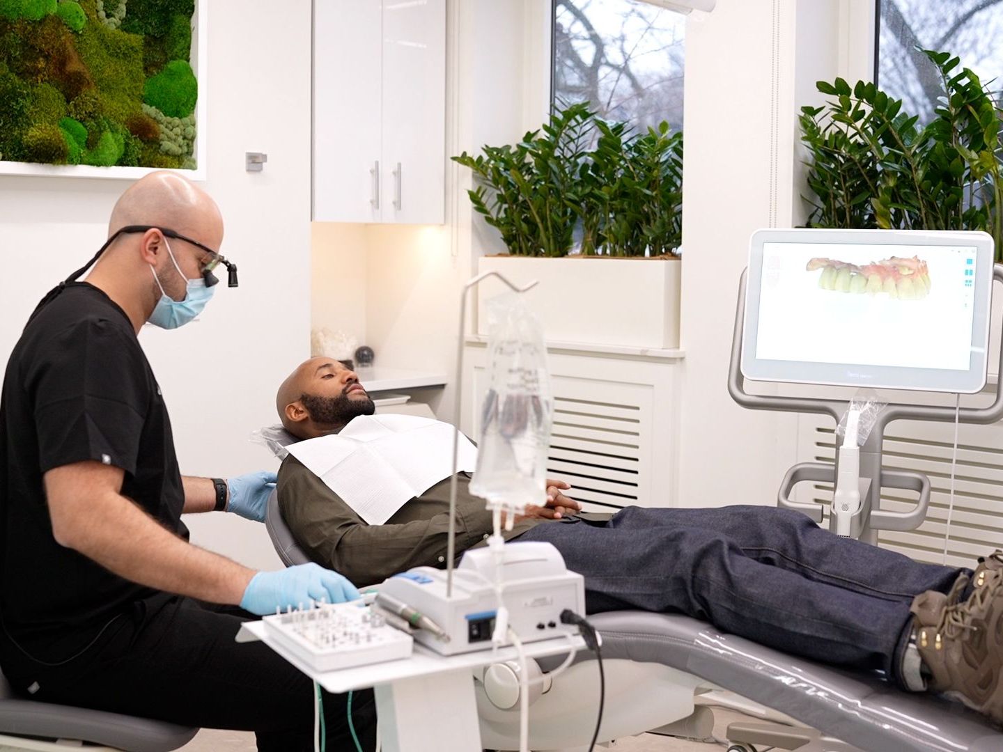 A man is laying in a dental chair while a dentist examines his teeth