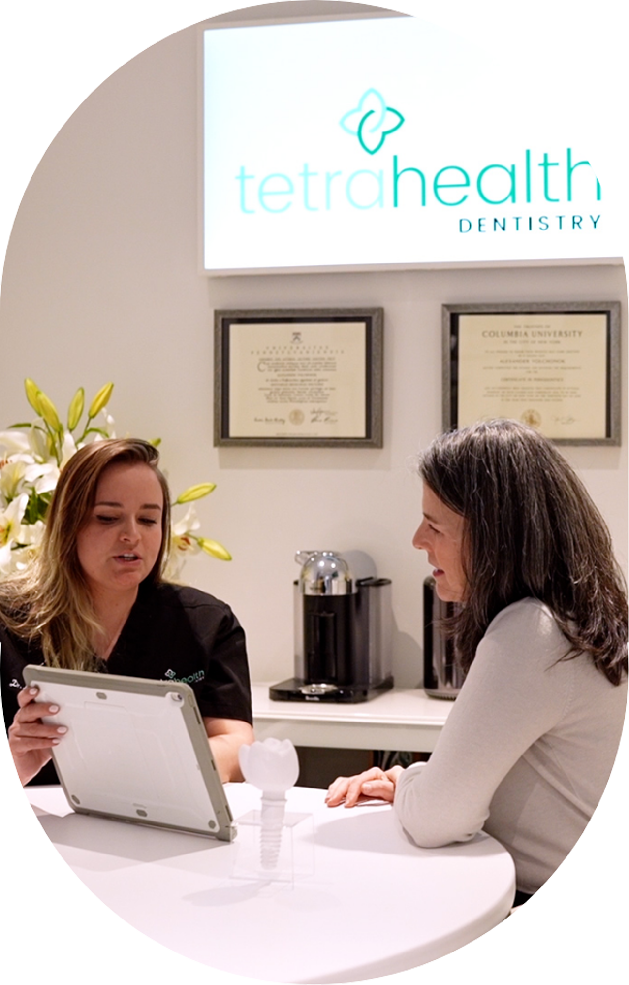 Two women are sitting at a table looking at a tablet