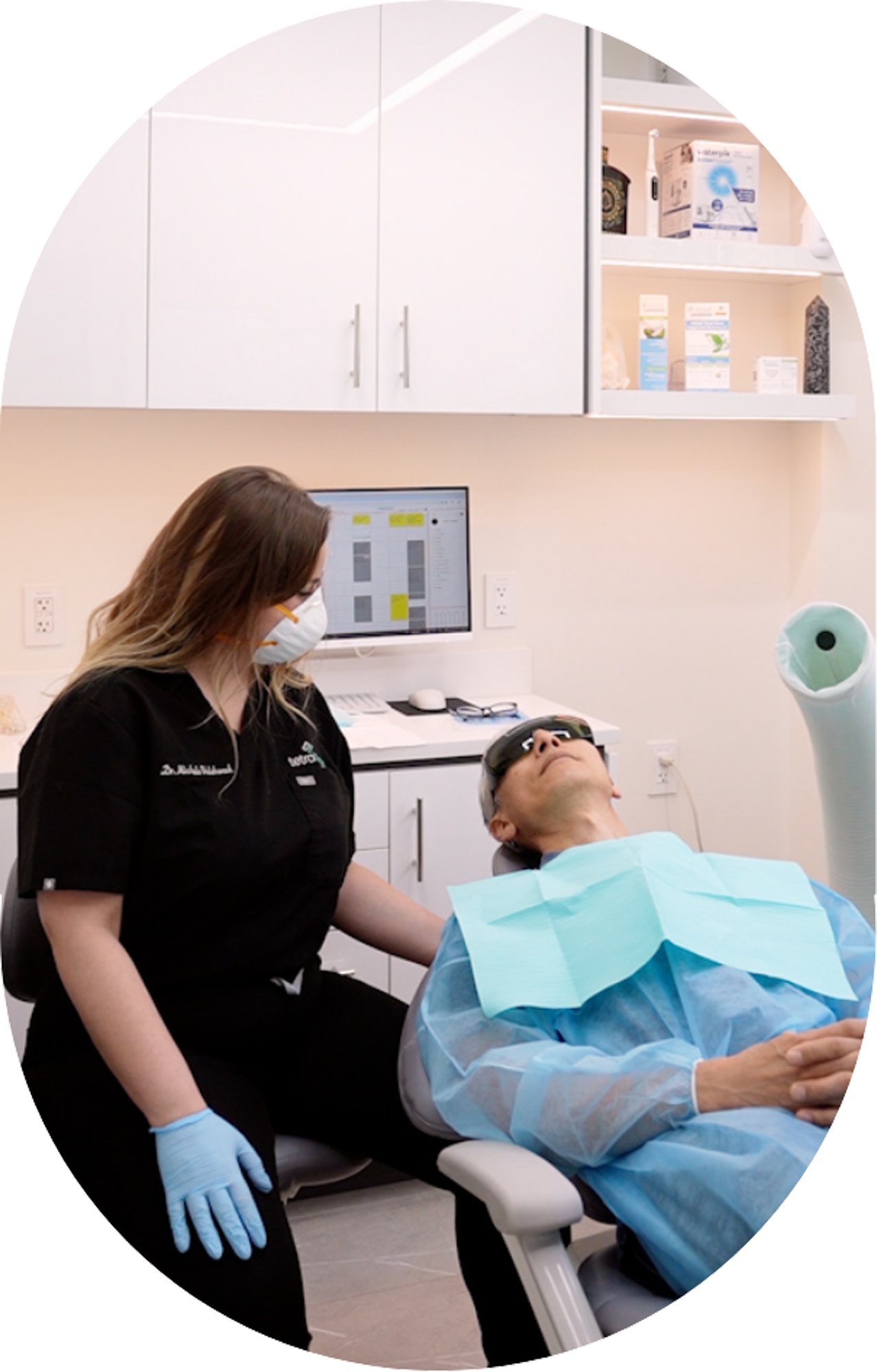 A woman is standing next to a patient in a dental chair