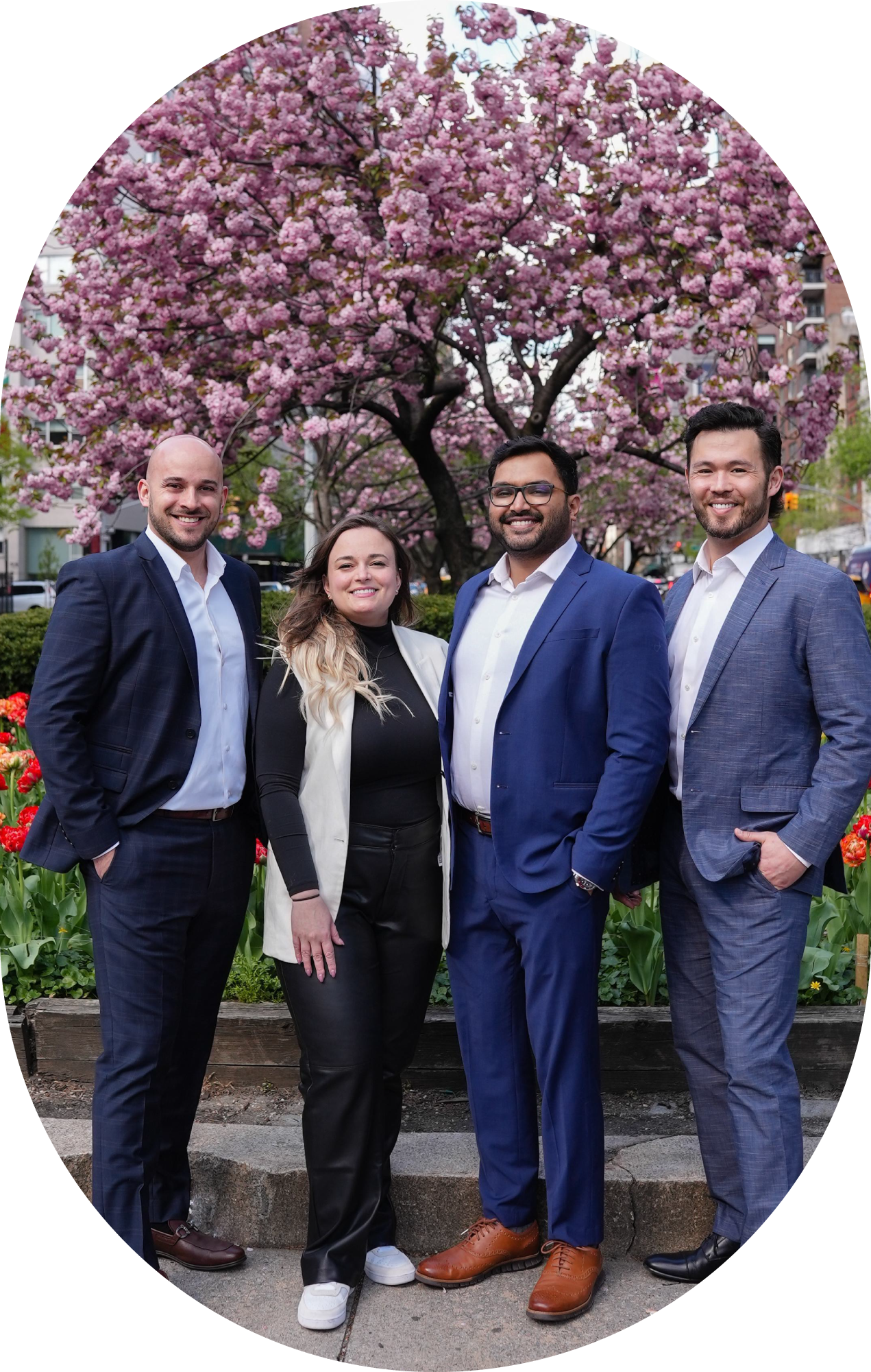 A group of people are posing for a picture in front of a cherry blossom tree.