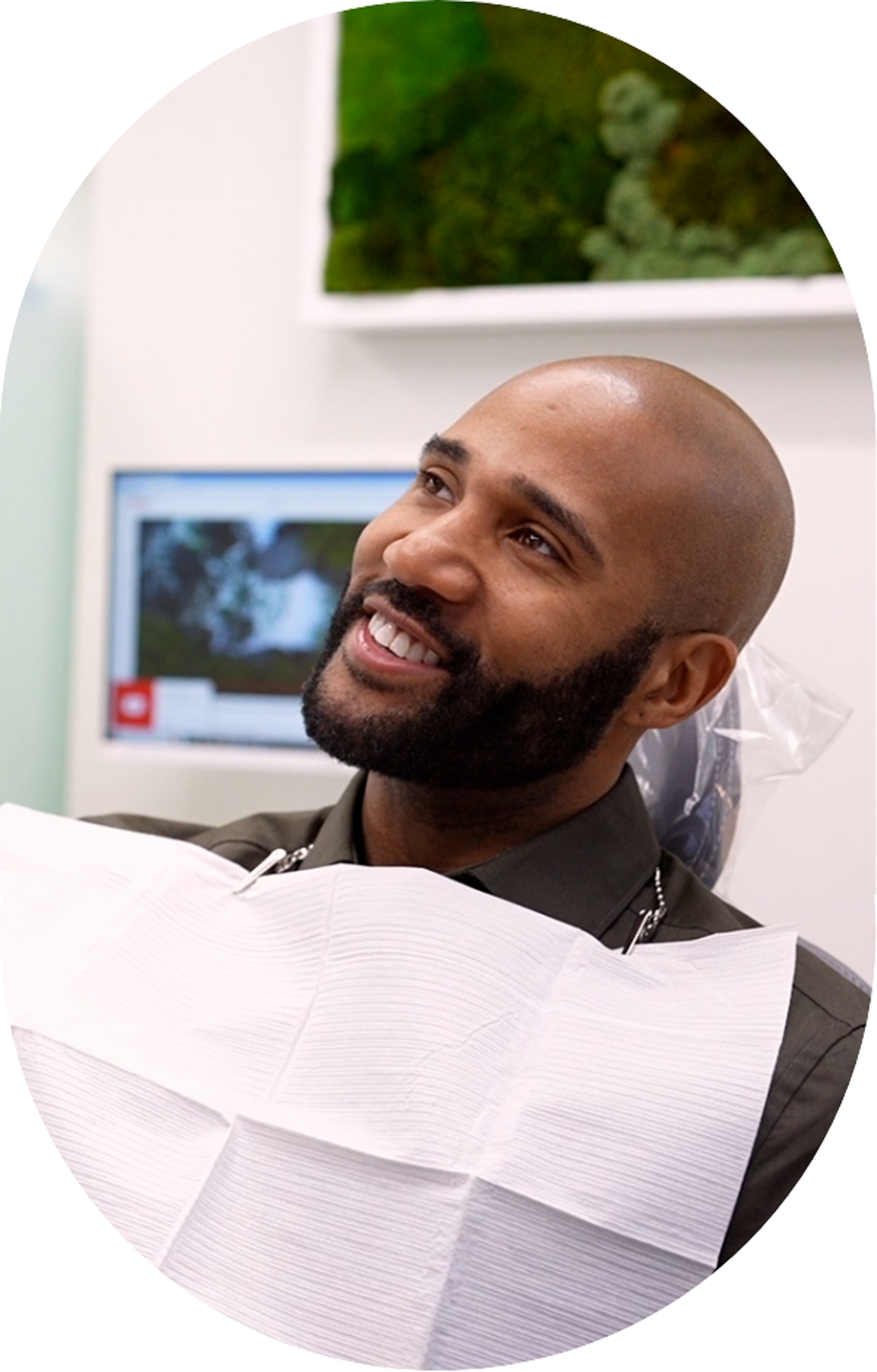 A man with a beard is sitting in a dental chair and smiling