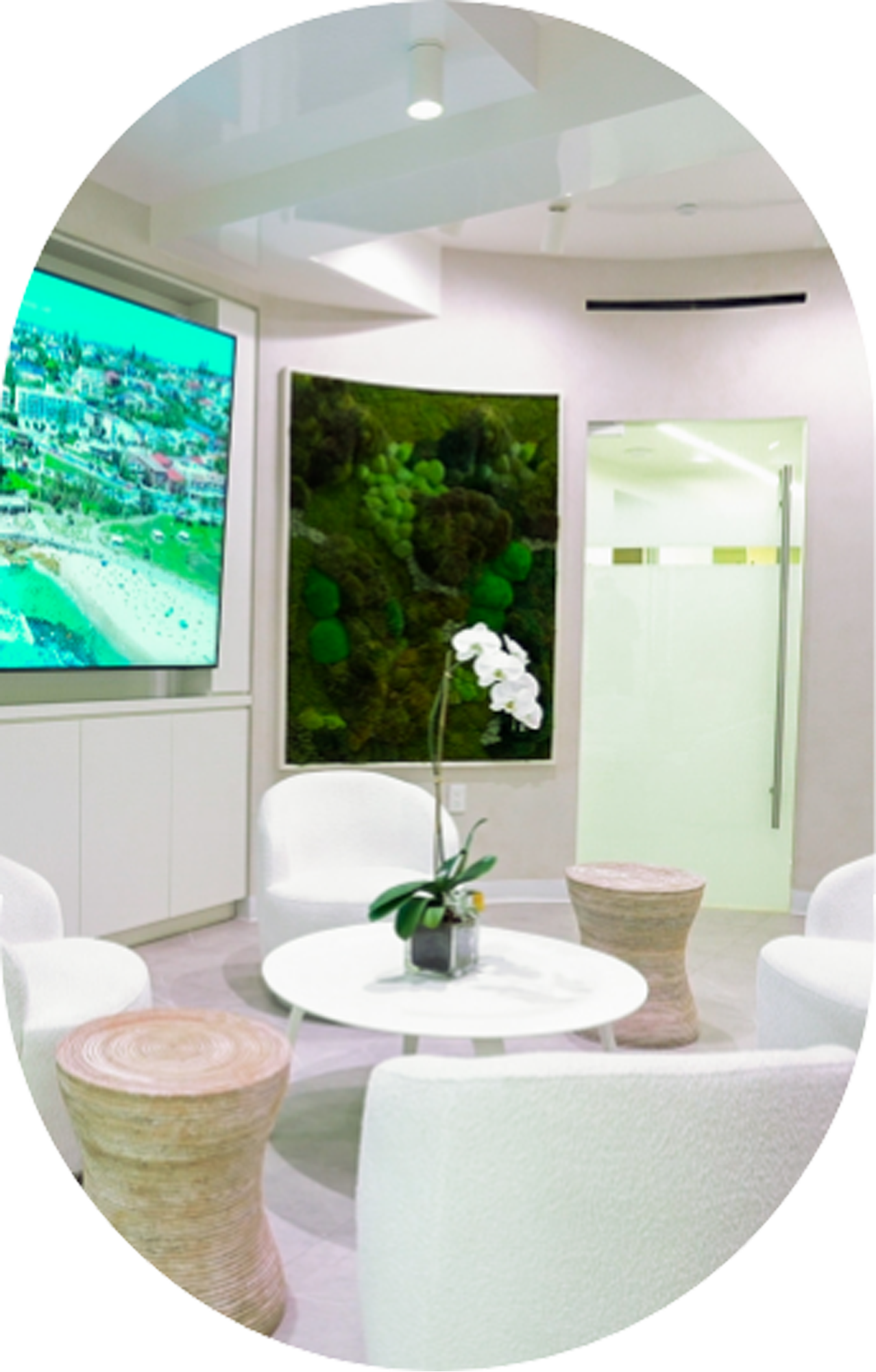 A waiting room with white furniture and a large flat screen tv