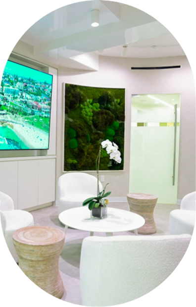 A waiting room with white furniture and a large flat screen tv