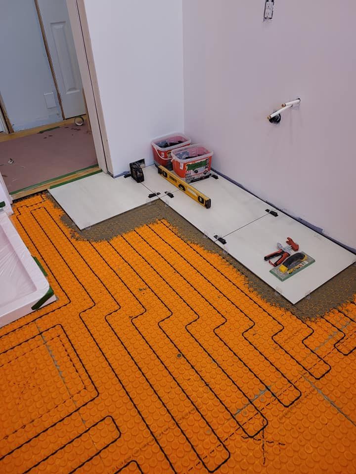 Une salle de bain en construction avec du carrelage en cours d'installation au sol